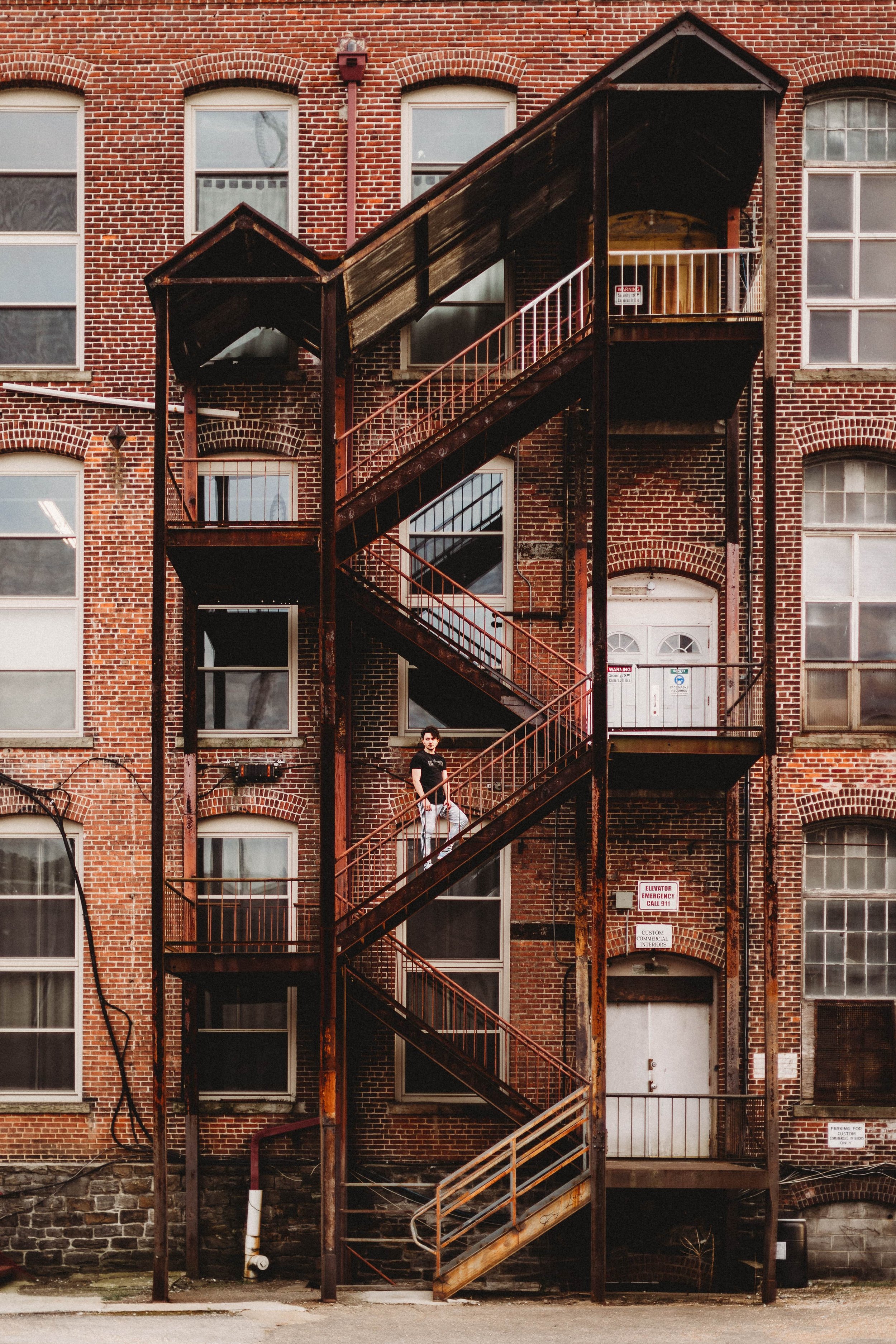 Person standing on exterior metal staircase of brick building