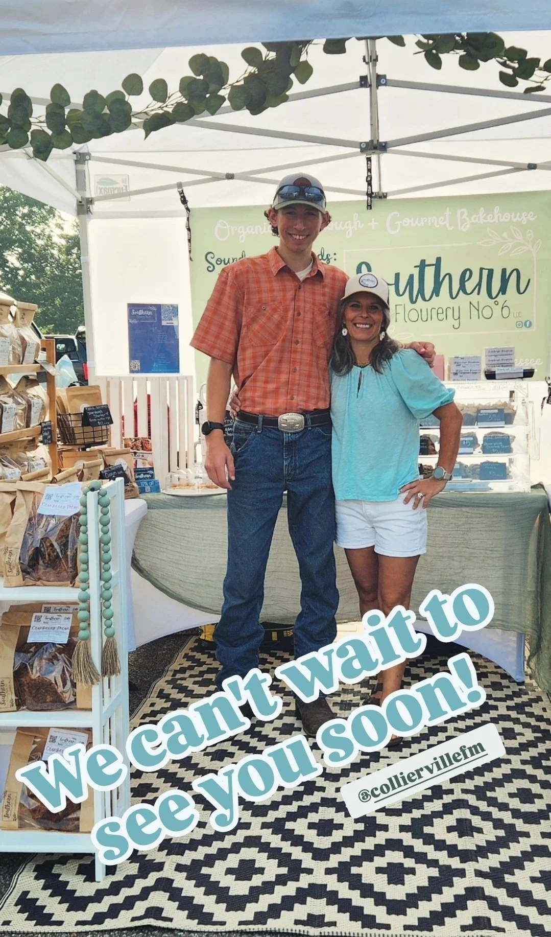 Two people, a young man and a woman, smiling and standing close together in front of a booth at an outdoor market. The booth has a sign that reads "Southern Flourery No. 6" and displays baked goods and products. The man wears a plaid orange shirt and jeans, while the woman wears a light blue blouse and white shorts. The caption on the image says, "We can't wait to see you soon!" with an Instagram handle @coliervillefilm.