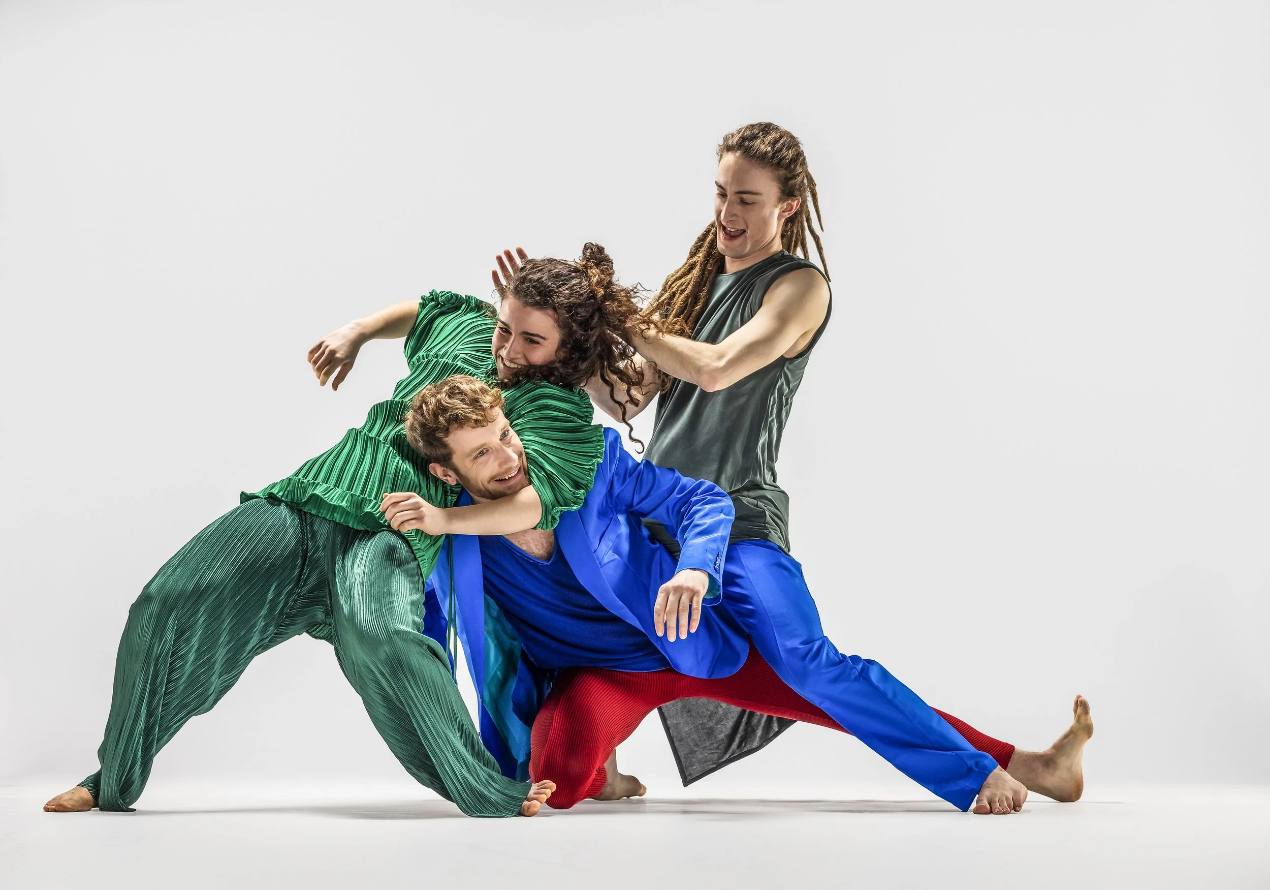 Three people dancing and playing together on a white background, laughing and engaging in lively movement.