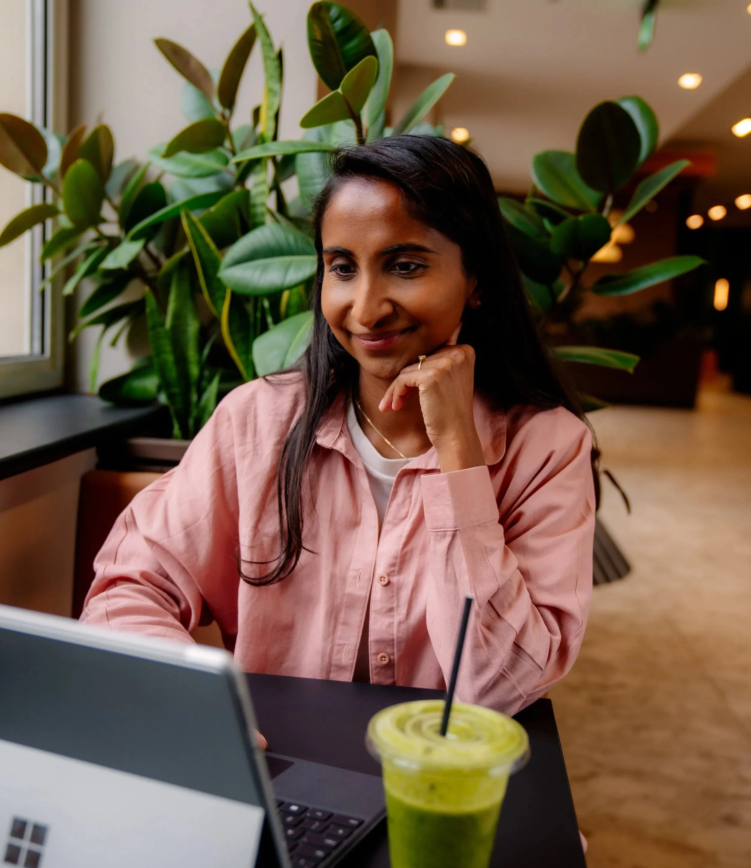Female financial adviser on a meeting and drinking smoothie with a plant behind her