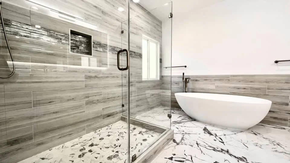 Modern bathroom with glass shower enclosure, freestanding bathtub, and marble flooring.