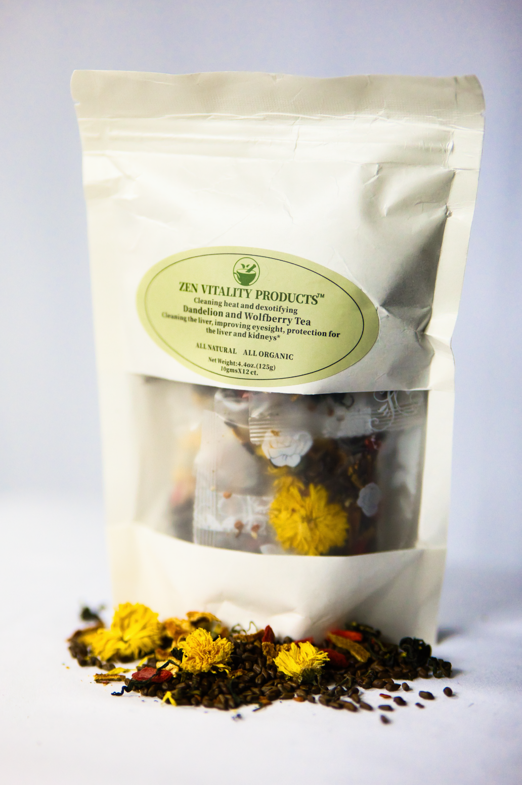 A white and silver herbal tea package labeled 'Zen Vitality Products' with dried flowers and tea leaves spilled in front.