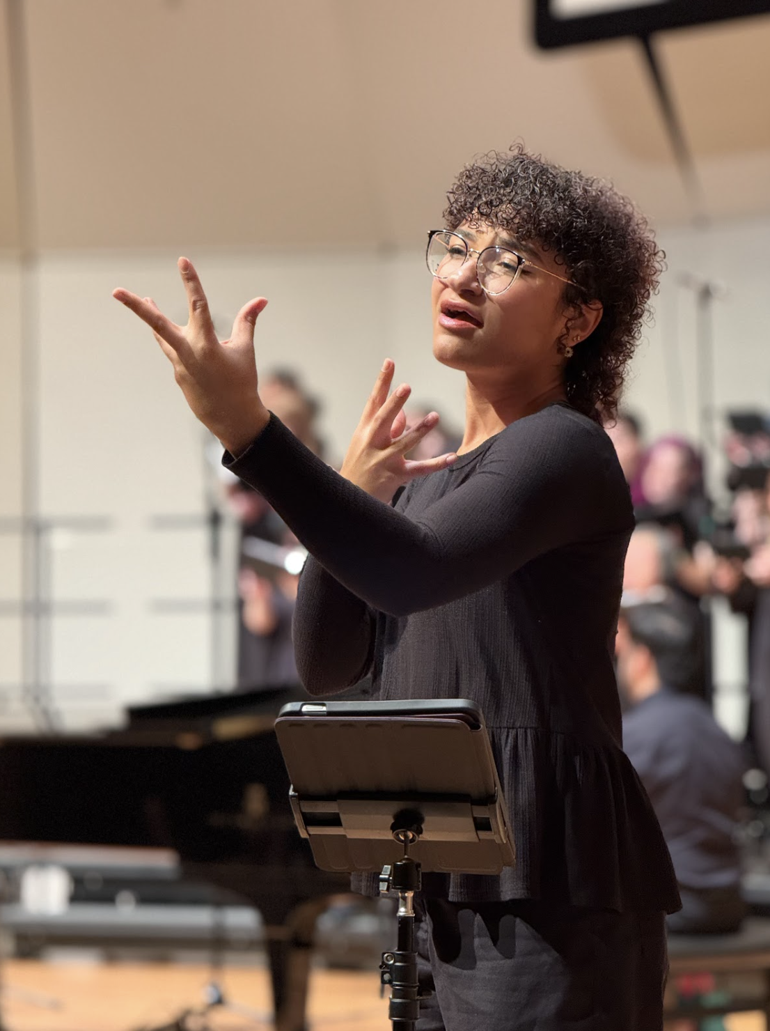 Selfie in profile angle of Makeda Duncan in front of white background. Makeda has short, coily black hair. Makeda wears squoval glasses, a blazer, and collared shirt. Makeda smiles, head tilted.