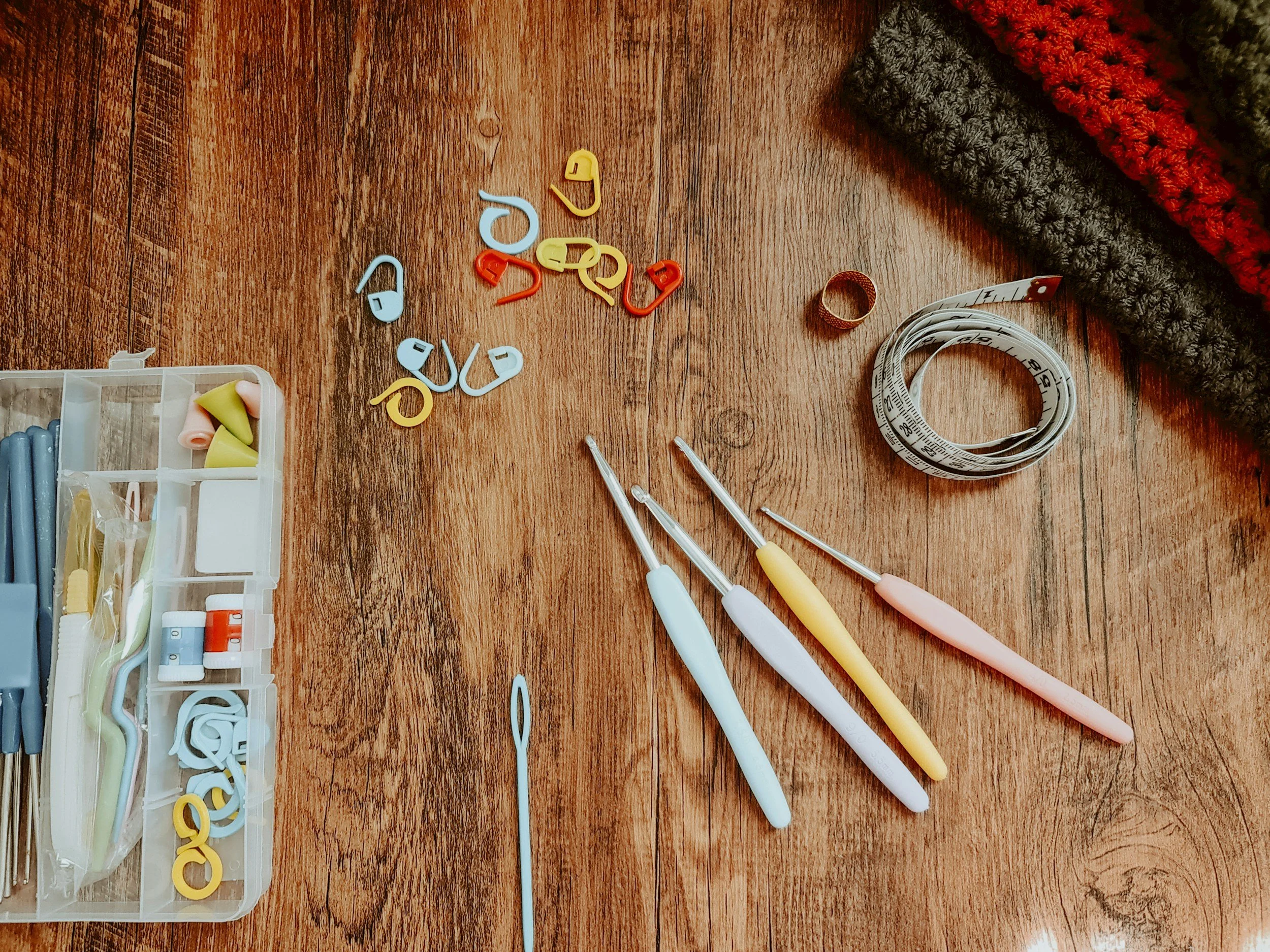 Colorful crochet and sewing supplies on a wooden table, demonstrating the way cozy hobbies help us be more present and embodied.