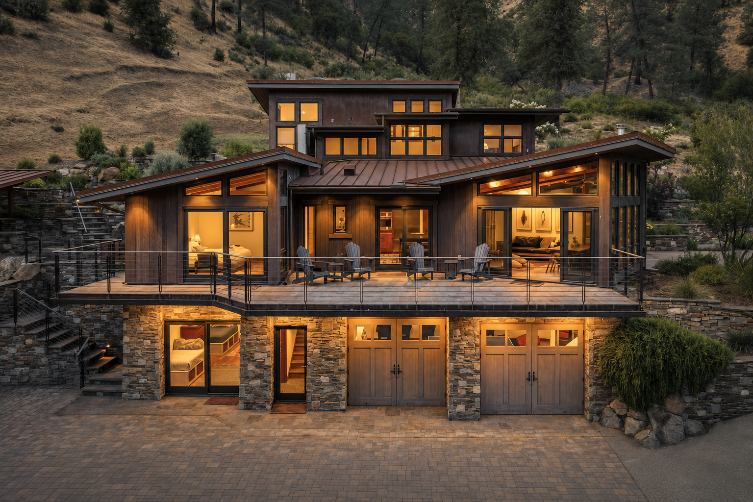 A multi-story modern house built into a hillside, featuring large glass windows, a spacious balcony, and stone accents, with warm interior lighting visible through the windows.