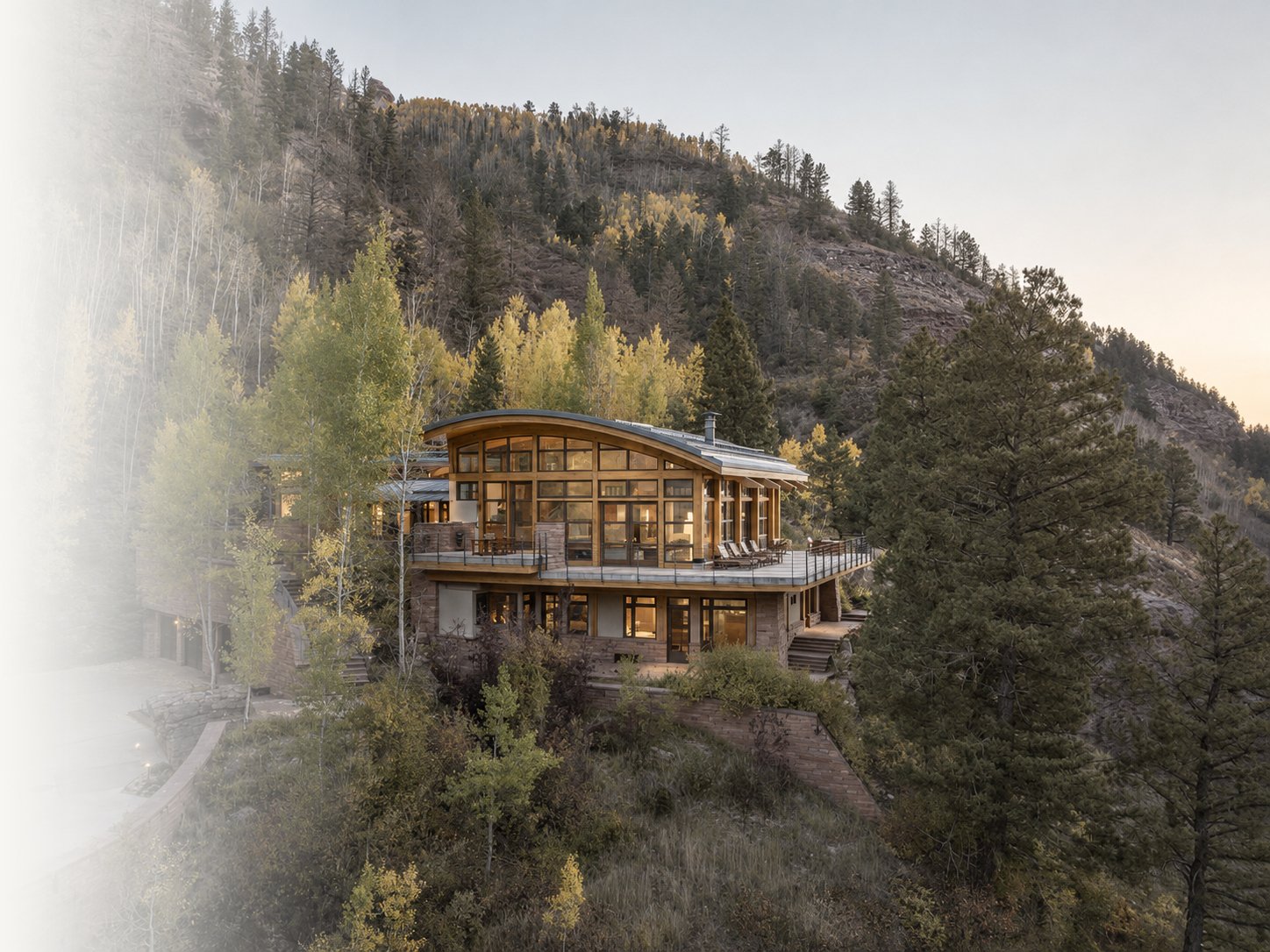 Mountainside modern residence with curved roof and large glass windows, supported through luxury furnishing, procurement, and project coordination.