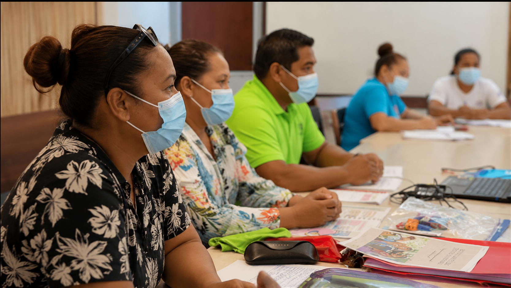 Groupe de personnes assises à une table lors d'une formation hygiène et sécurité, toutes portant des masques faciaux.