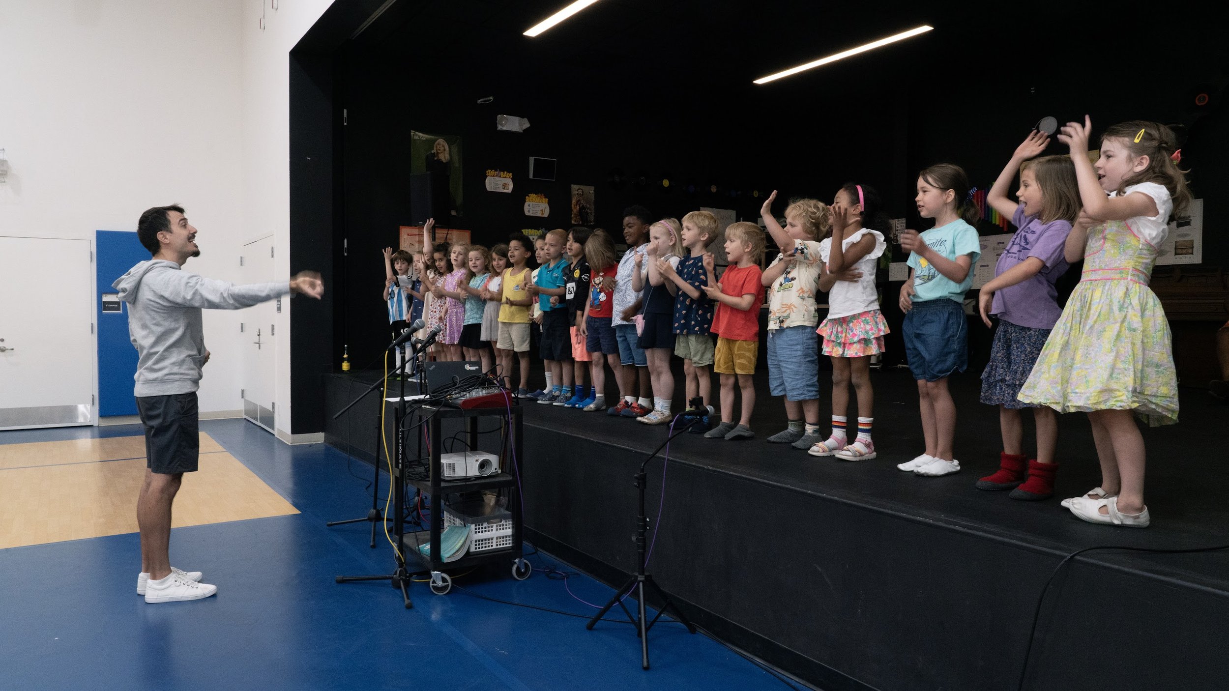 Students standing on a stage learning to dance from teacher