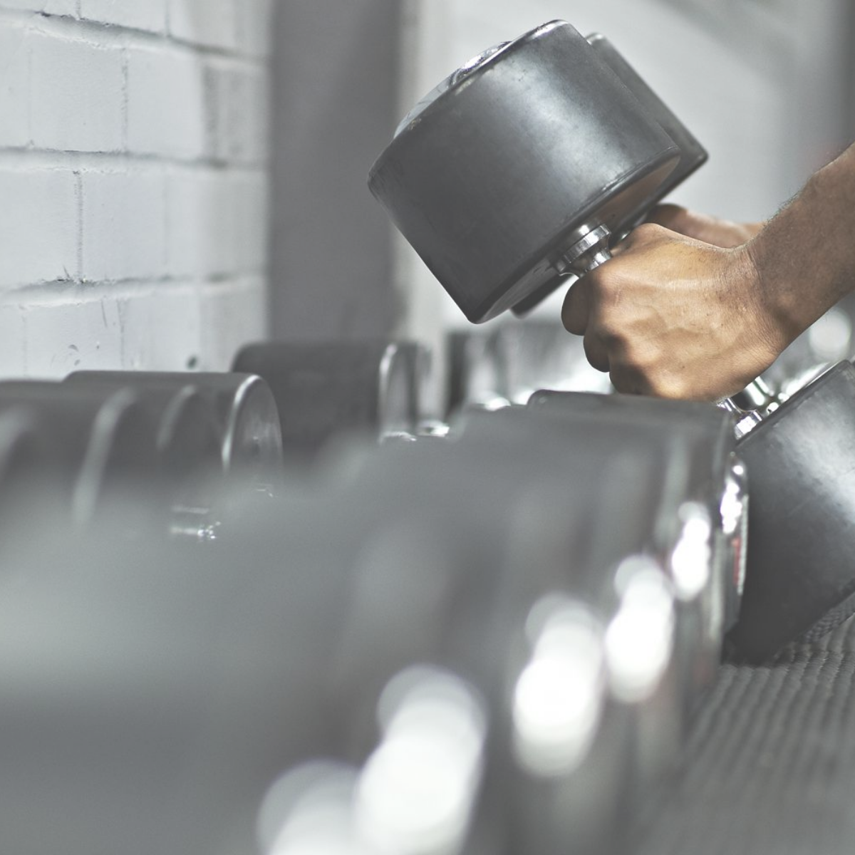Person lifting a dumbbell in a gym or fitness setting.