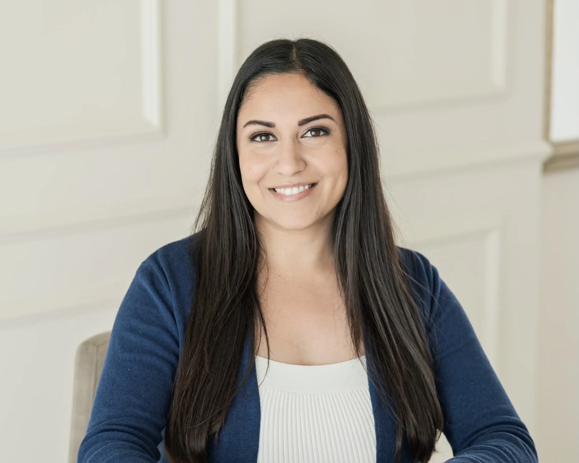 Featured photo of Auria Zahed, MS, LMFT wearing a blue cardigan and white top, smiling softly. Page highlights her licensed therapy services within the inclusive, trauma-informed wellness collective supporting women and gender-expansive clients.