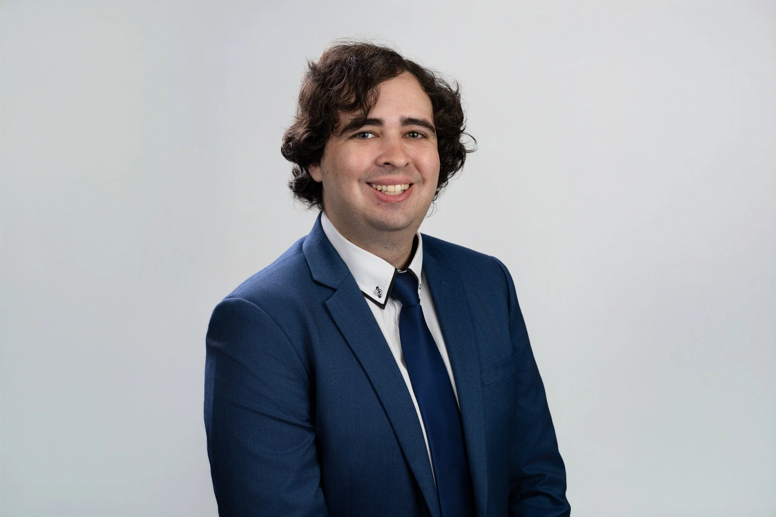 Professional business portrait photographer image of man in blue suit smiling at camera.