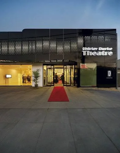 The entrance of the Shirley Burke Theatre with a red carpet leading inside, during evening hours, welcoming the AABC Competition participants.