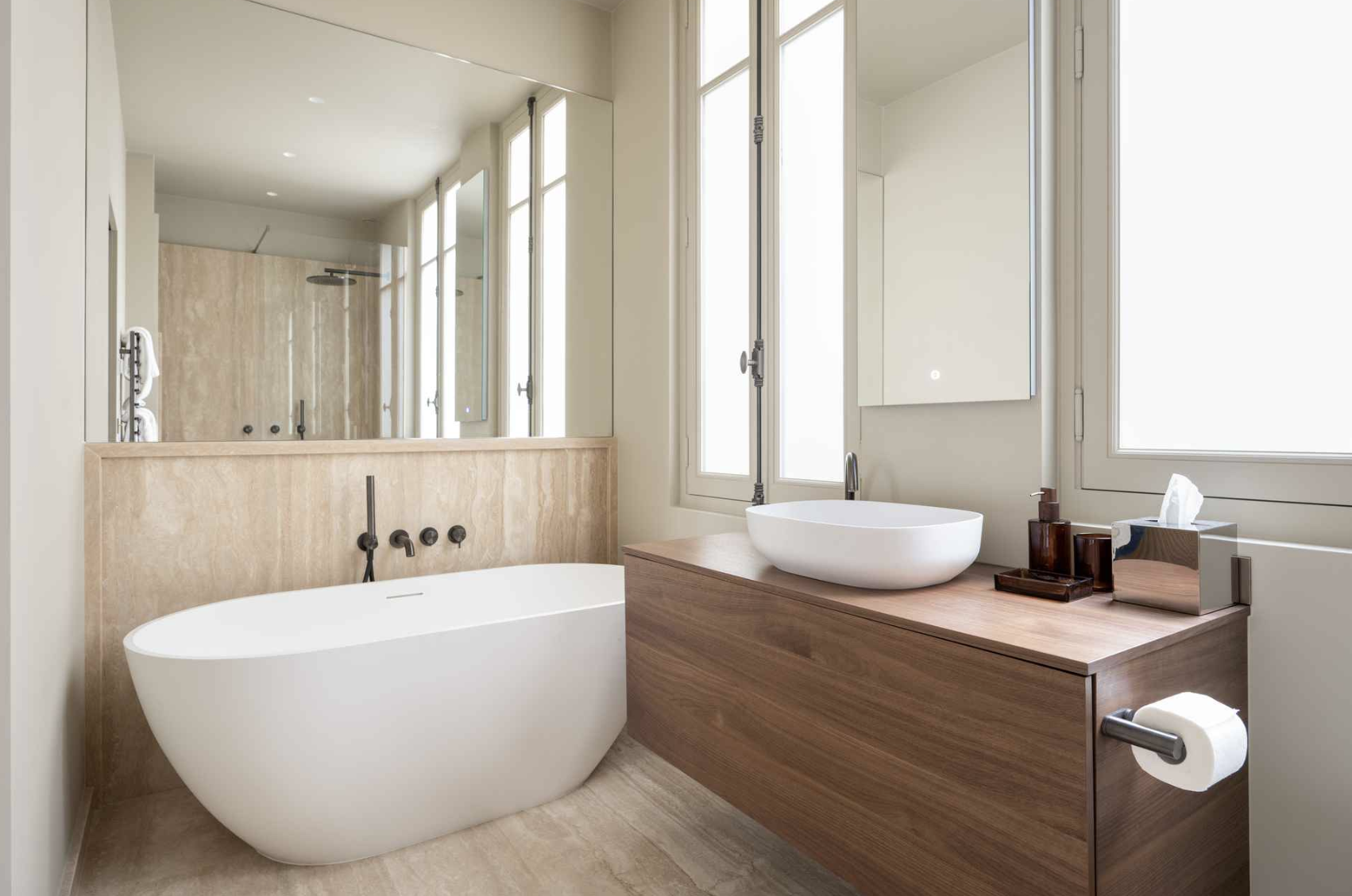 Modern bathroom featuring a freestanding bathtub, wooden vanity with vessel sink, large mirror, and windows with natural light.