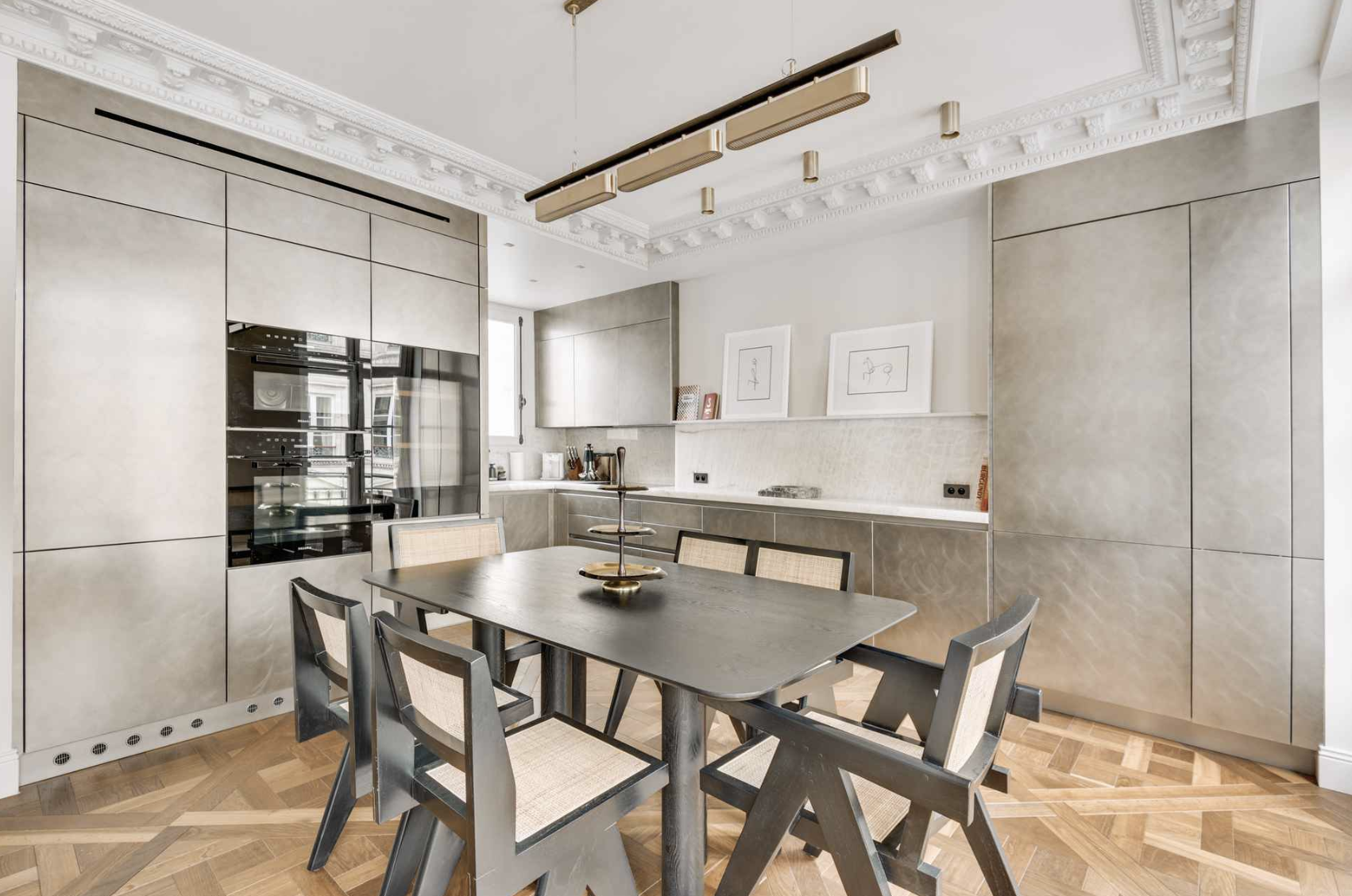 Modern kitchen with beige cabinetry, a black dining table with six chairs, and a light wooden parquet floor.