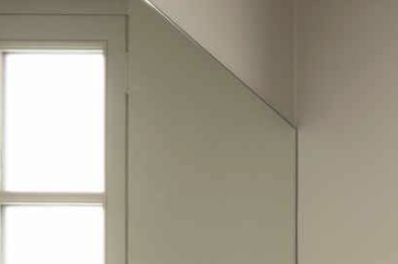 Part of a room with a window, a mirror, and a plain wall.