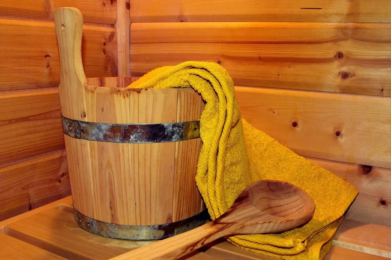 Holzsauna mit gelber Handtuch, Holzschaufel, und Holzbank in einer Sauna aus Holz.