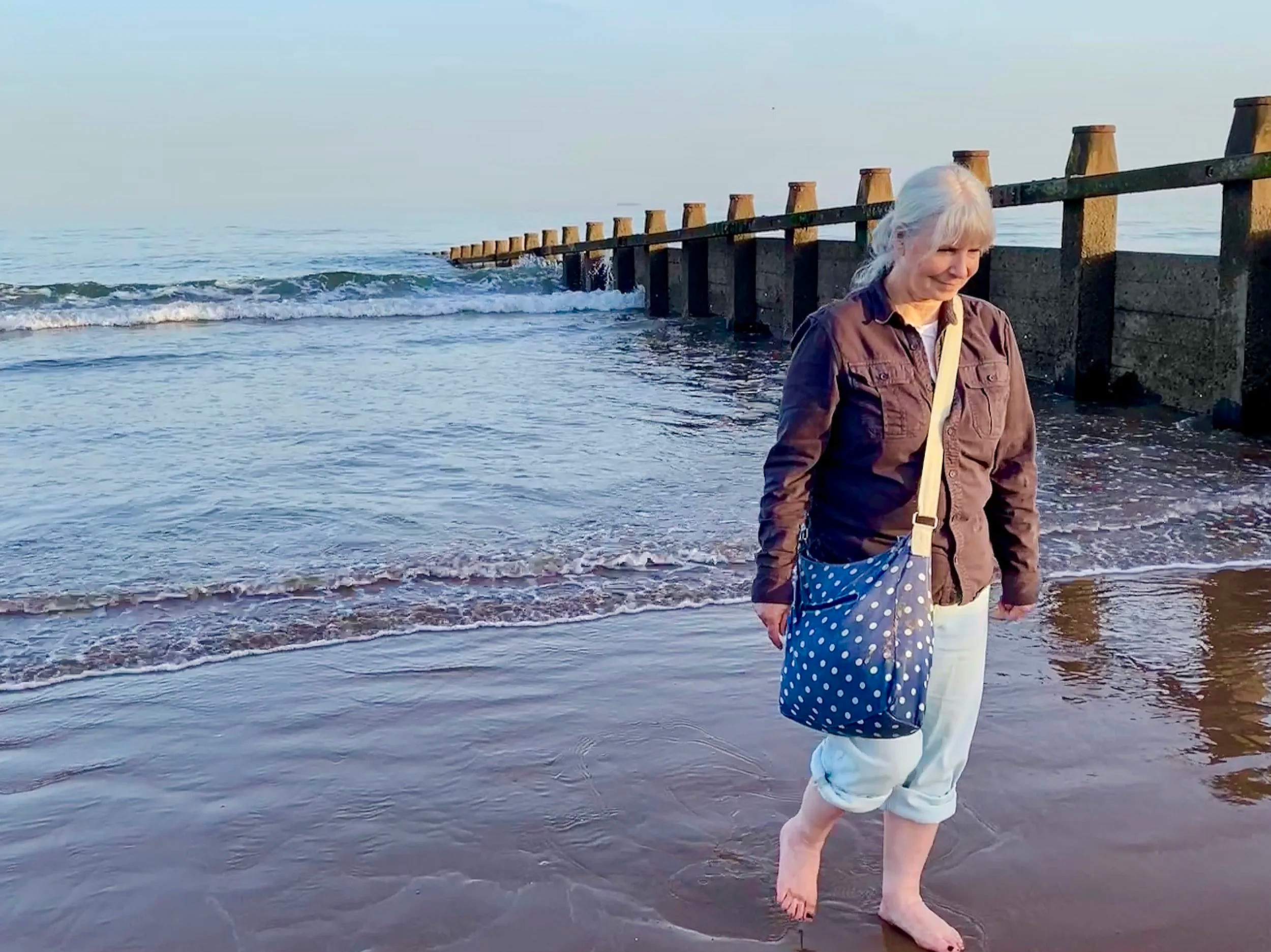 Nicola walks barefoot from the sea