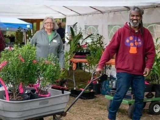 Photo of a smiling man pulling a cart with plants in it,  at PlantFest 2024.