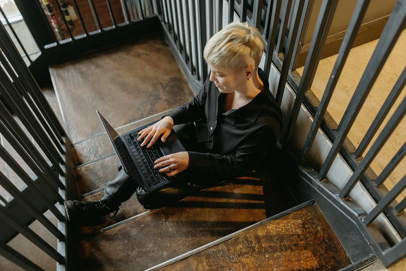 An SEO Strategist sitting on stairs with her laptop on creating a customized visibility strategy for a local business