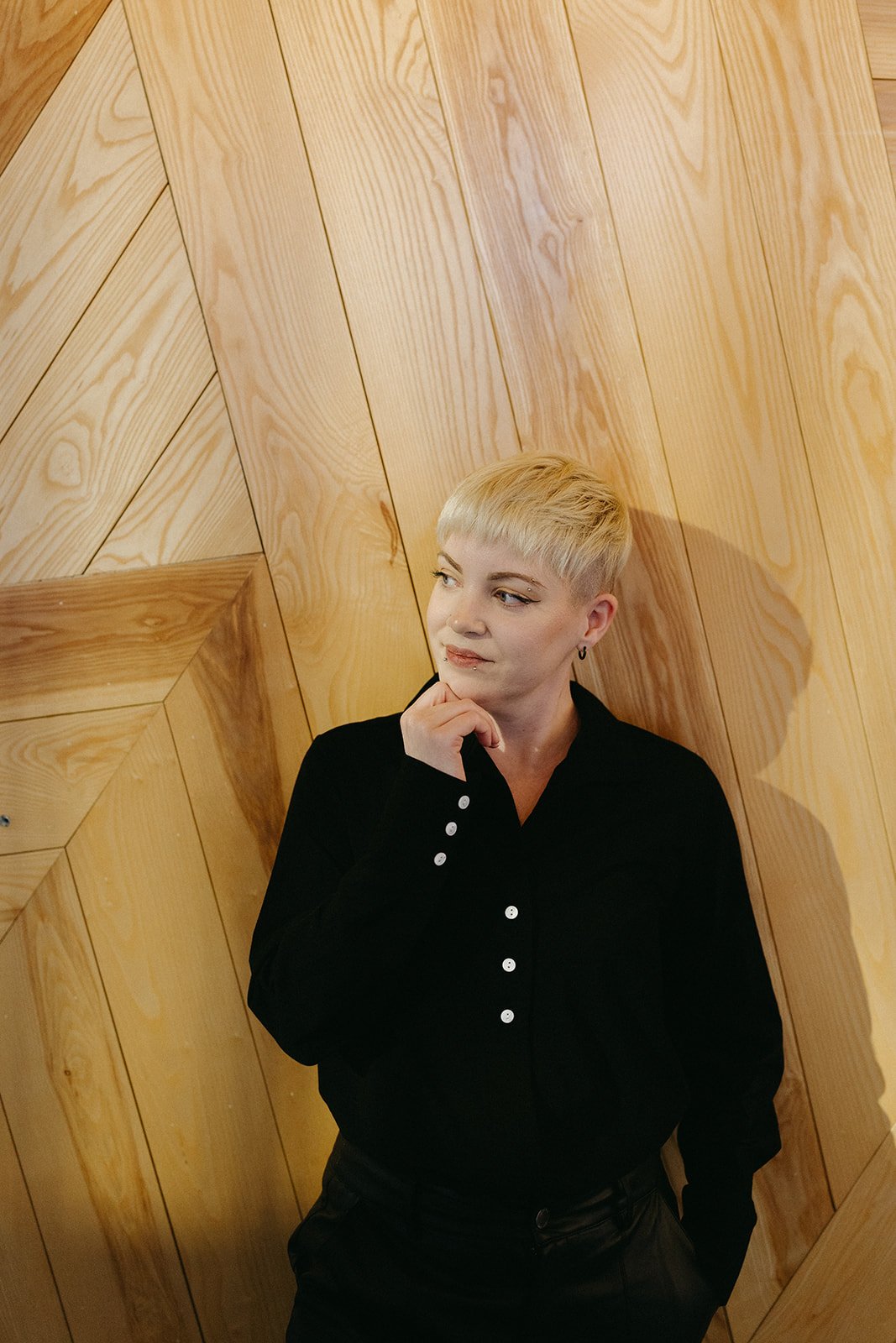 Professional expert in SEO for Real Estate Agents stands against a wood plank wall looking off to the left side