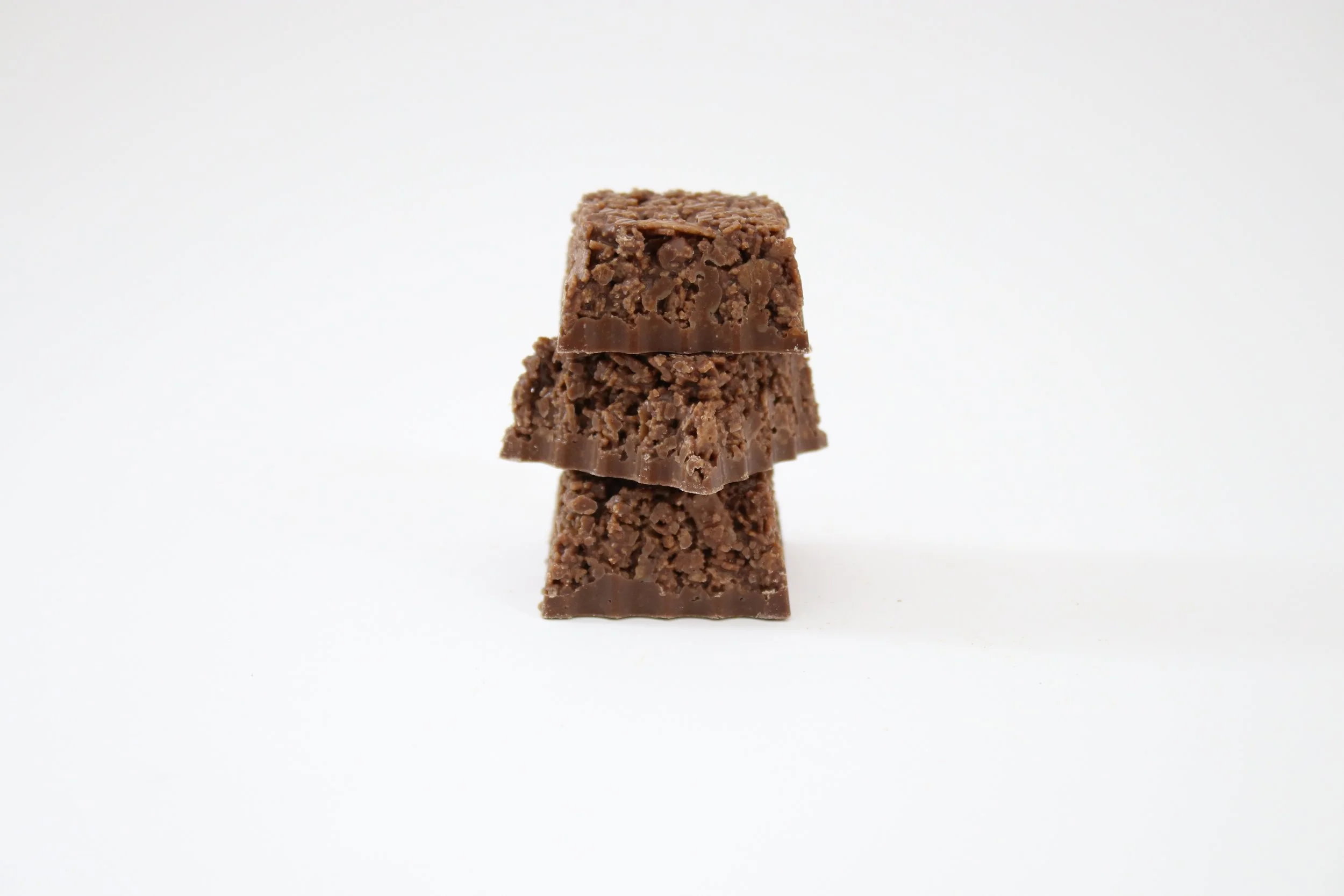 Three stacked pieces of chocolate fudge on a white background.
