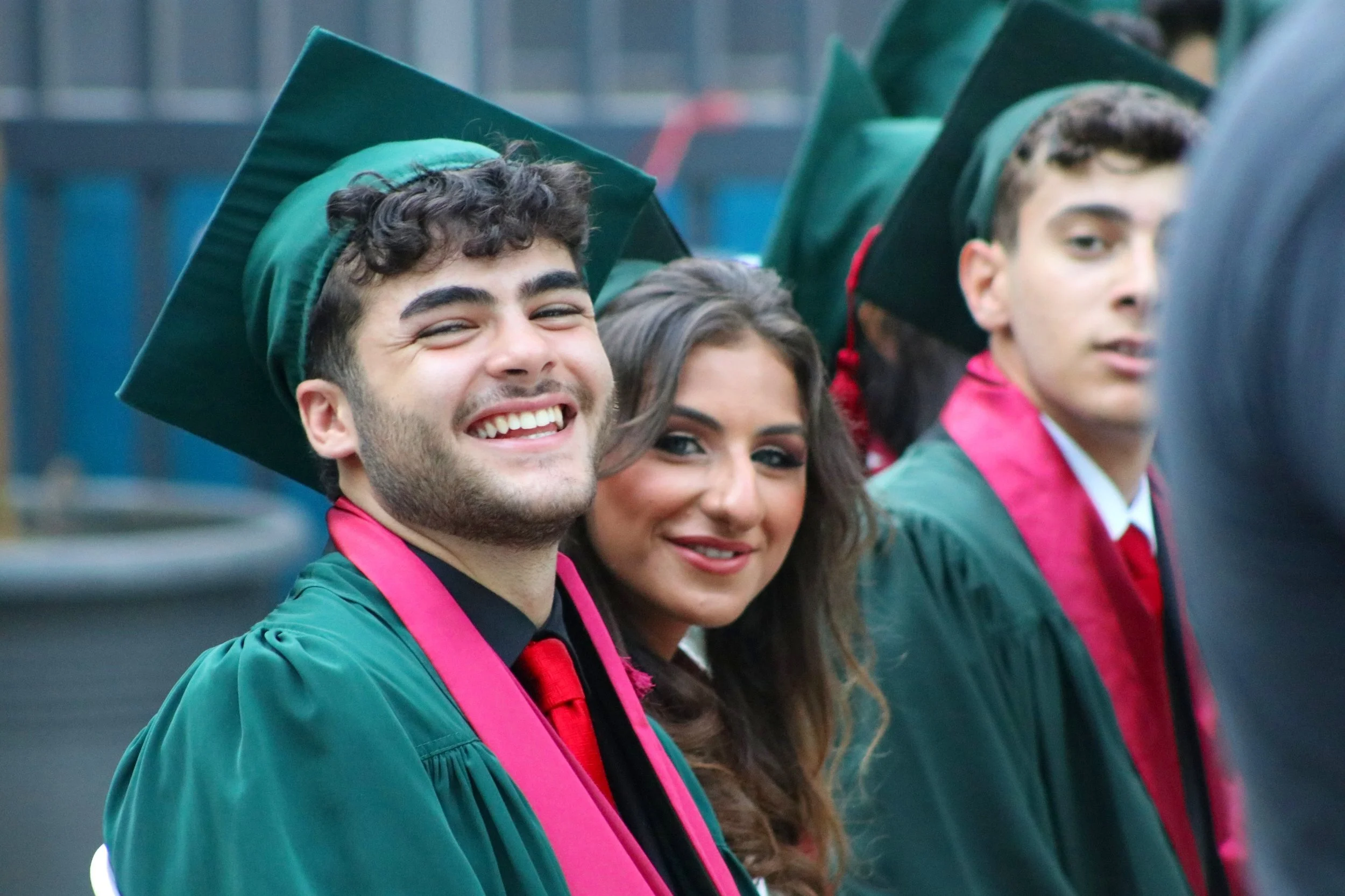 A group of graduates in academic caps and gowns, smiling at a graduation ceremony.