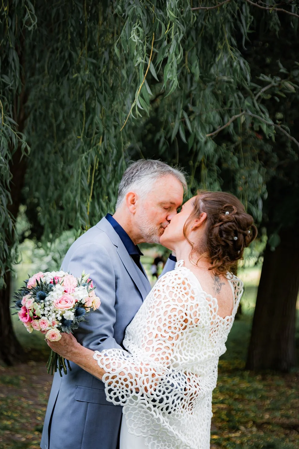 Mariés s’embrassant sous les arbres lors de leur mariage à Tours, ambiance romantique et naturelle