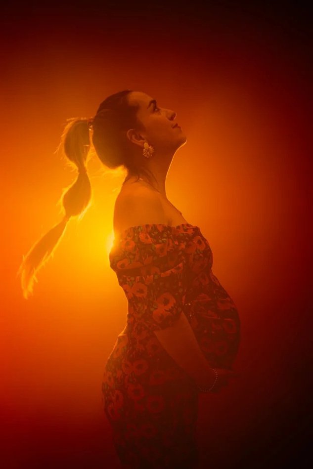 Portrait de grossesse en contre-jour, femme enceinte en lumière chaude orangée, séance photo artistique en studio à Tours
