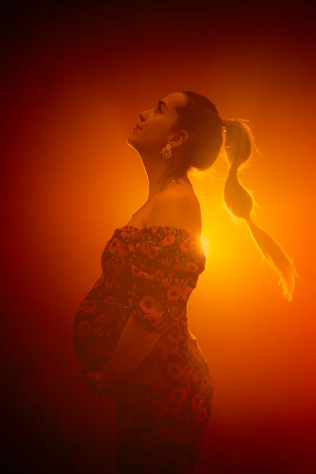 Portrait de grossesse en contre-jour, femme enceinte en lumière chaude orangée, séance photo artistique en studio à Tours