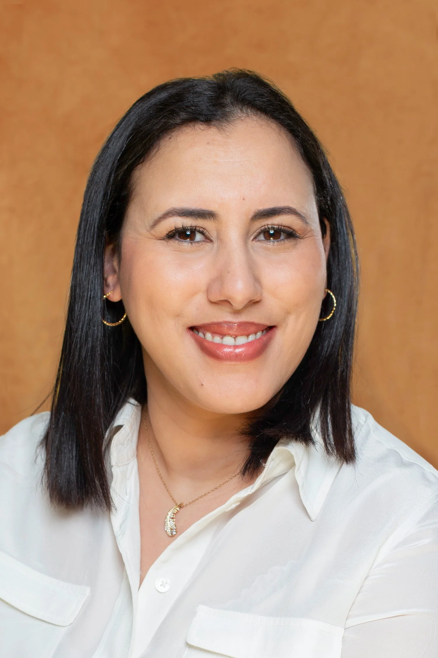 Portrait studio d’une femme souriante sur fond brun, éclairage doux et naturel – photo corporate élégante