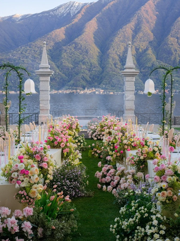 Candlelit aisle of pink, peach and yellow roses between dinner tables at dusk