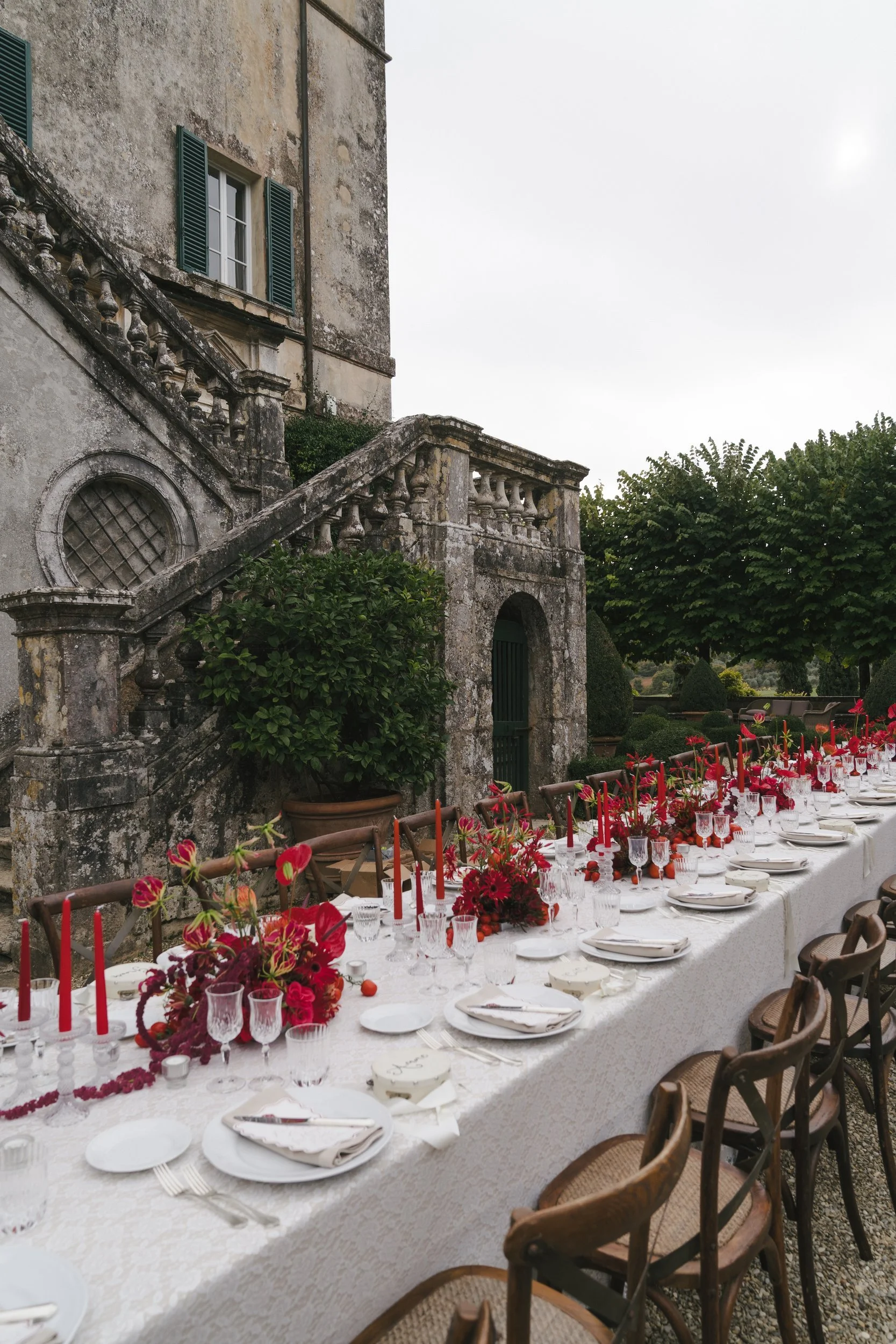 Lace tablecloth, crystal glasses and red taper candles along a welcome dinner table leading to Villa Cetinale's stone staircase