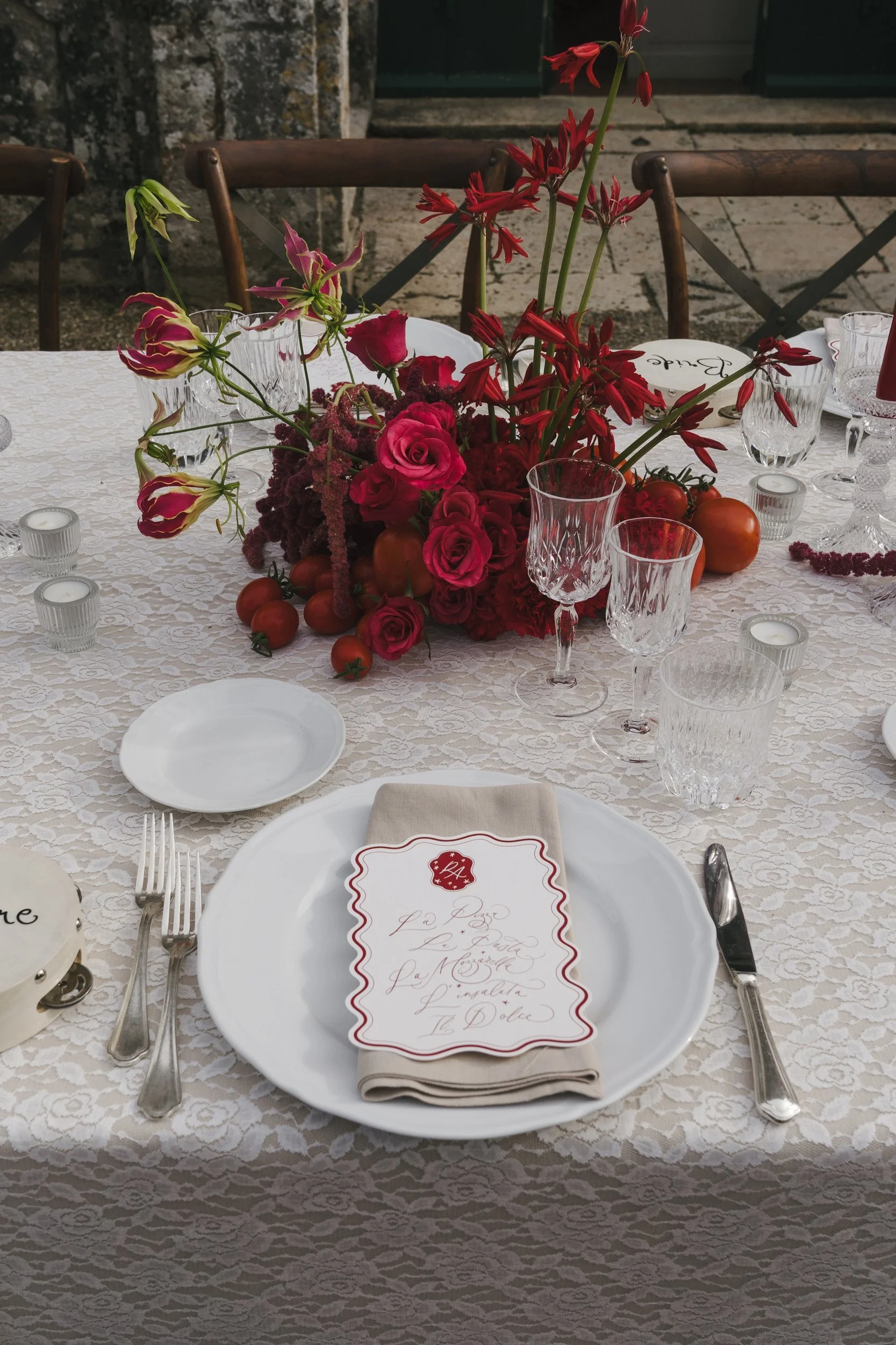 Place setting on vintage lace with linen napkin, scalloped calligraphy menu, silver cutlery and crystal glass