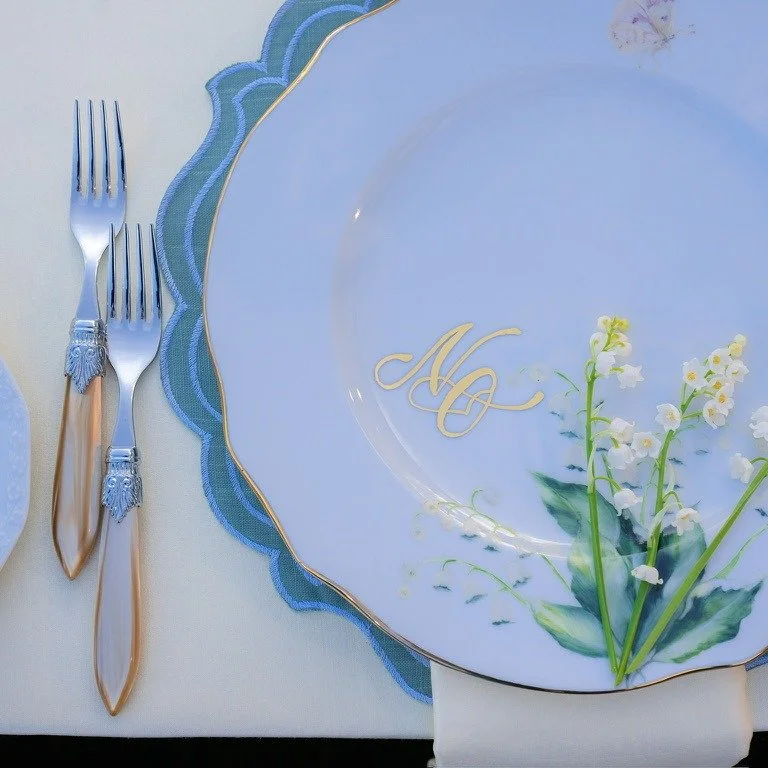 Lily of the valley on a monogrammed plate over a blue scalloped placemat