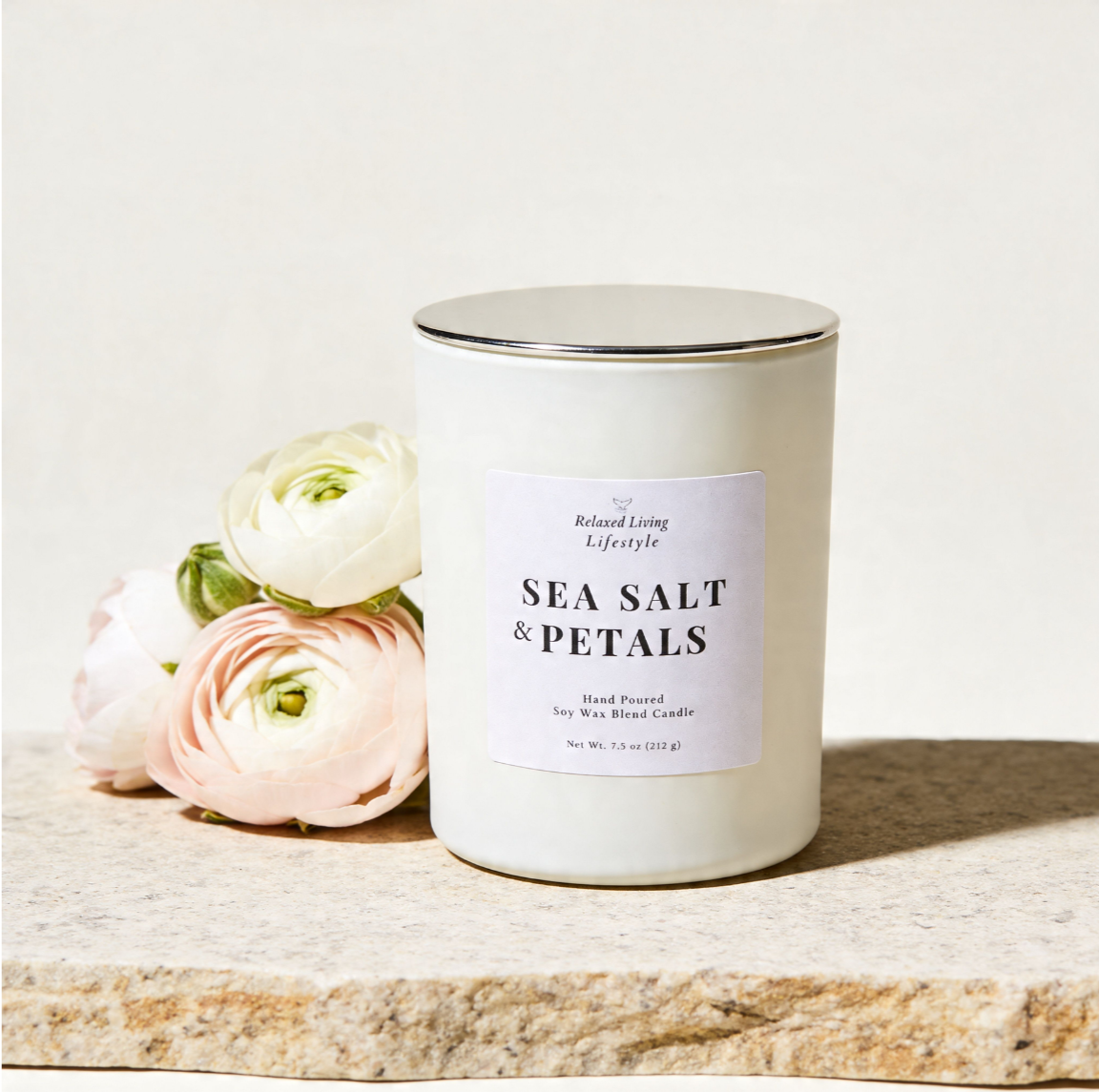 Sea Salt and Petals soy candle displayed on a textured stone surface with soft florals beside it, set against a neutral background, creating a clean coastal aesthetic with a light floral atmosphere