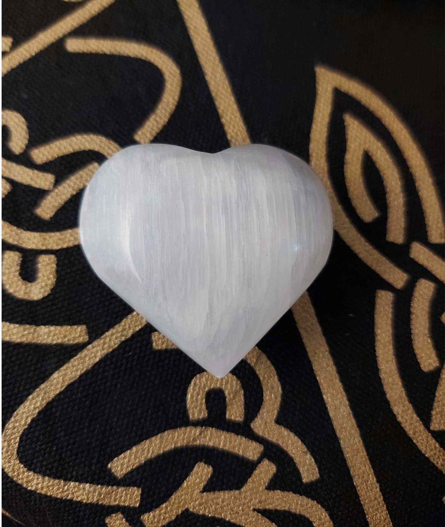 Polished Selenite Heart crystal resting on soft fabric-a calming healing stone for energy cleansing, meditation, and chakra balancing