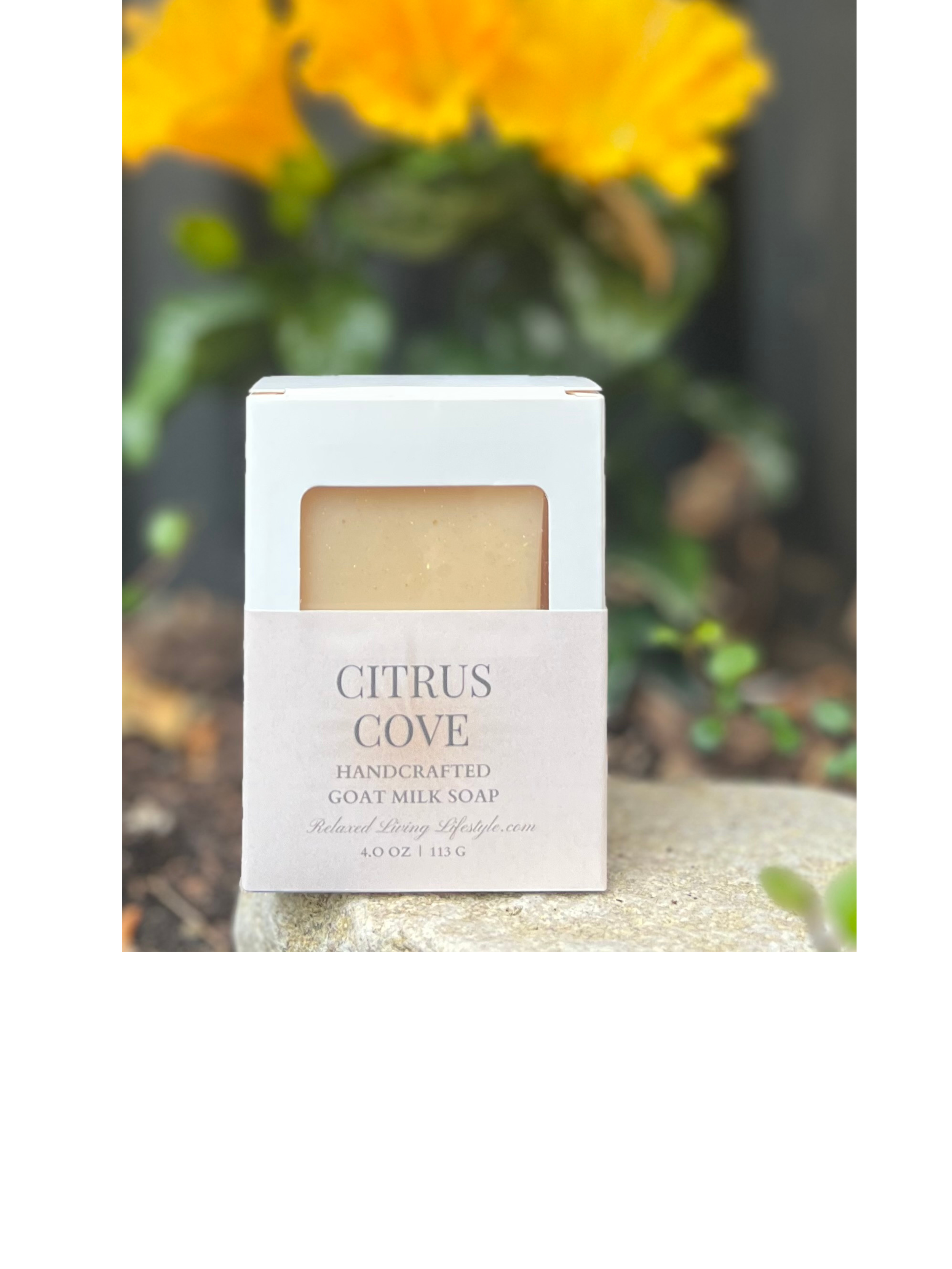 Handcrafted Citrus Cove goat milk soap bar with citrus and honey, styled with a bright orange flowers
