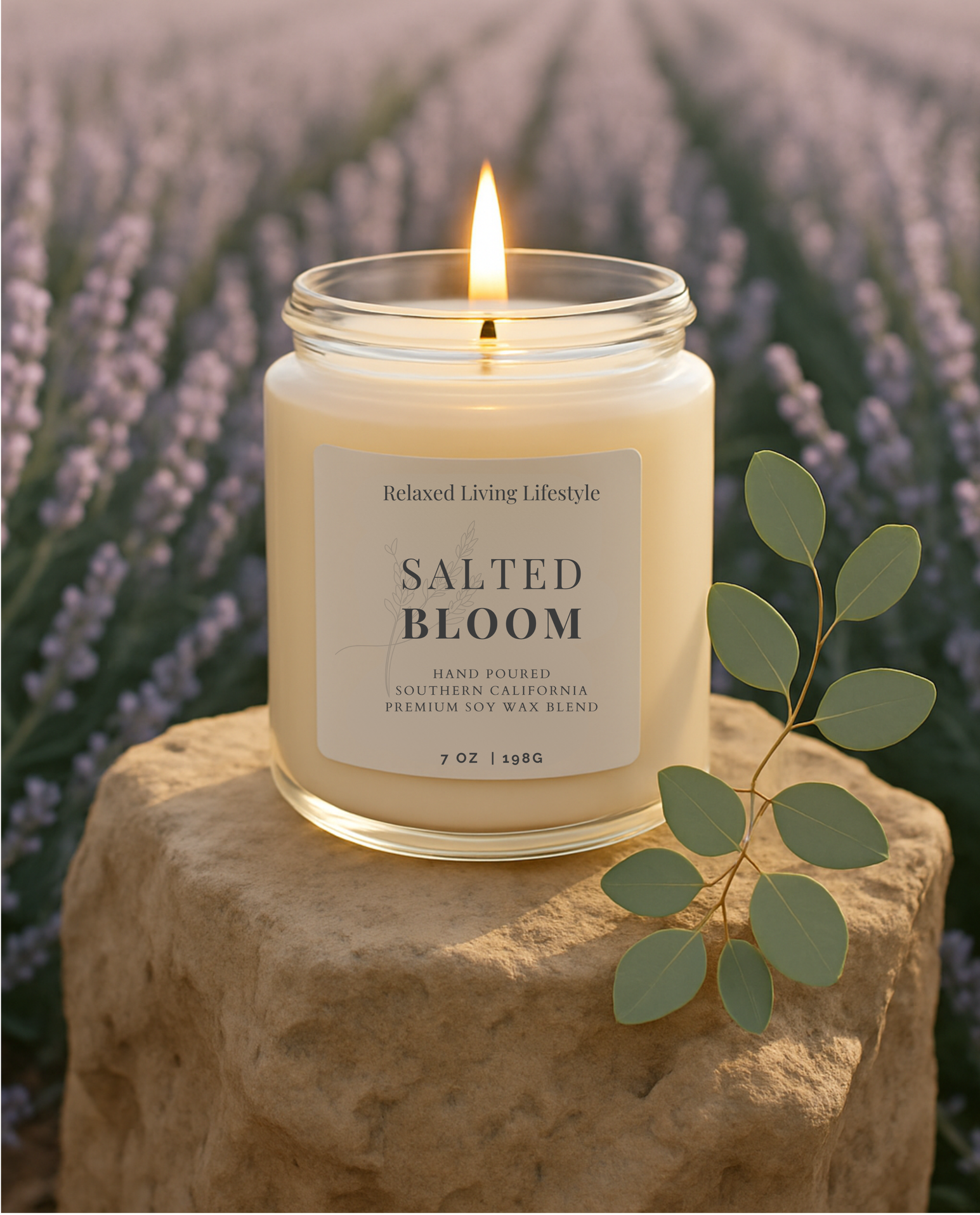 7 oz Salted Bloom candle with lavender, citrus and cedar notes displayed in nature with the candle lit