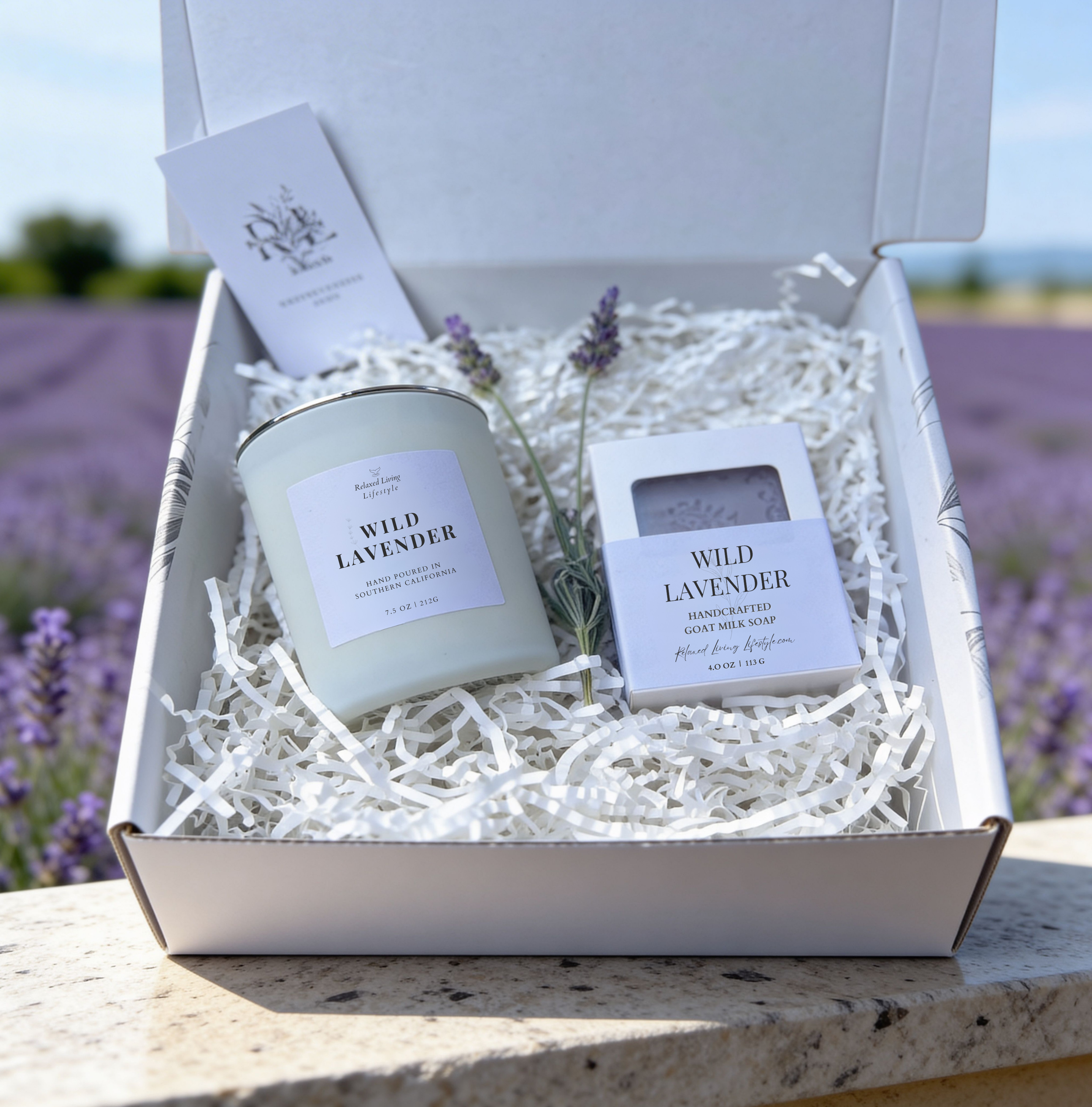 Lavender candle and soap gift set with chamomile and sandalwood, styled on a textured surface with a soft blurred lavender field background