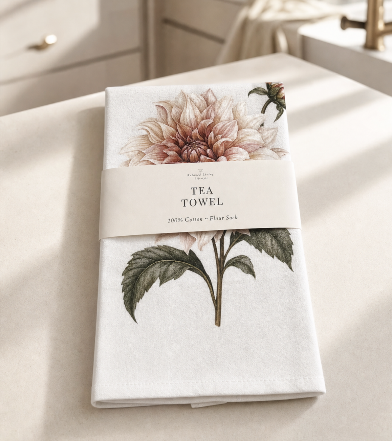 Botanical dahlia print cotton tea towel in blush and sage tones, banded label, styled in a bright luxury kitchen
