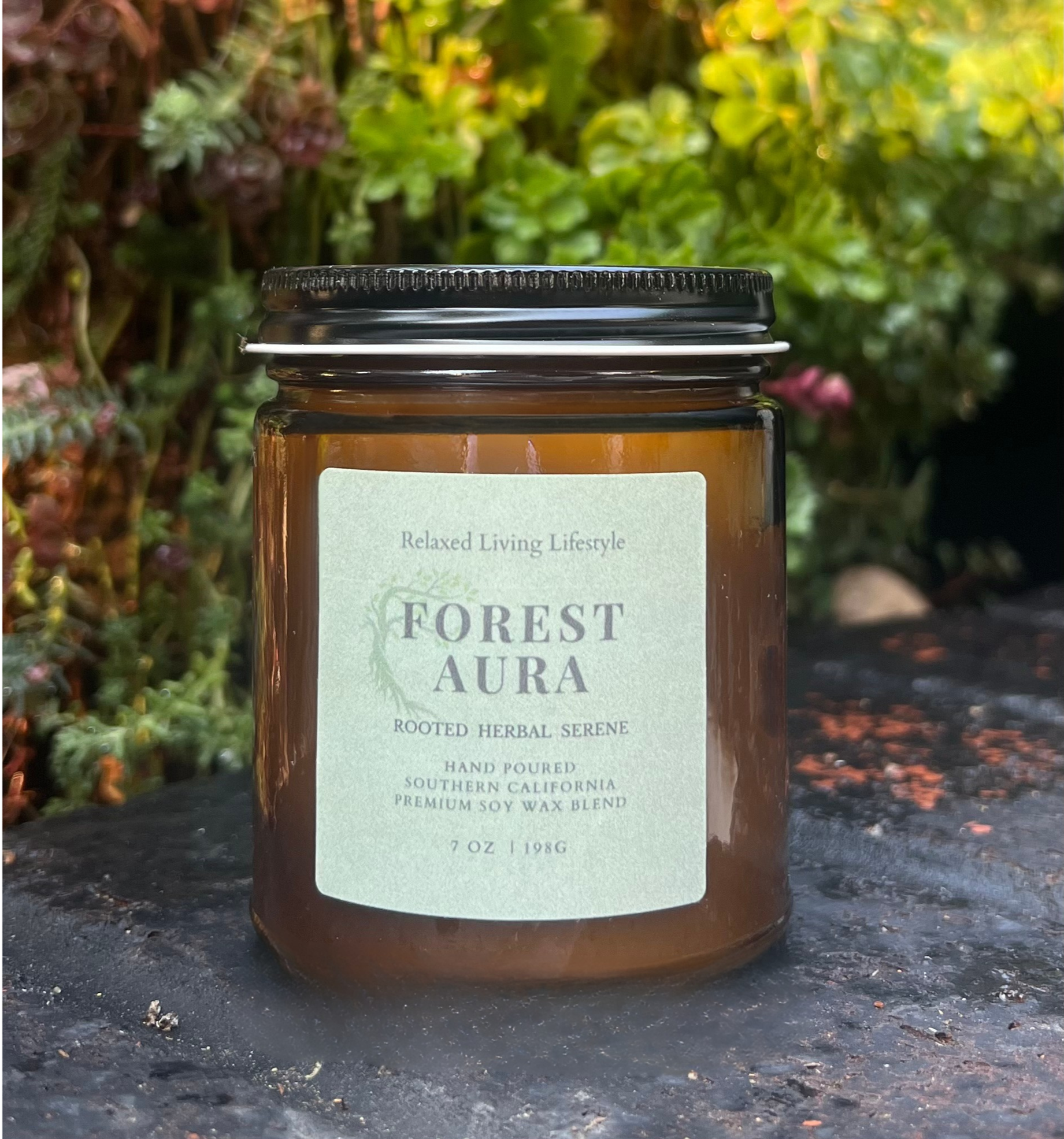 Forest Aura candle with earthy, herbal notes of peppercorn, sage, moss and patchouli sitting on a tree stump in a mystical forest setting