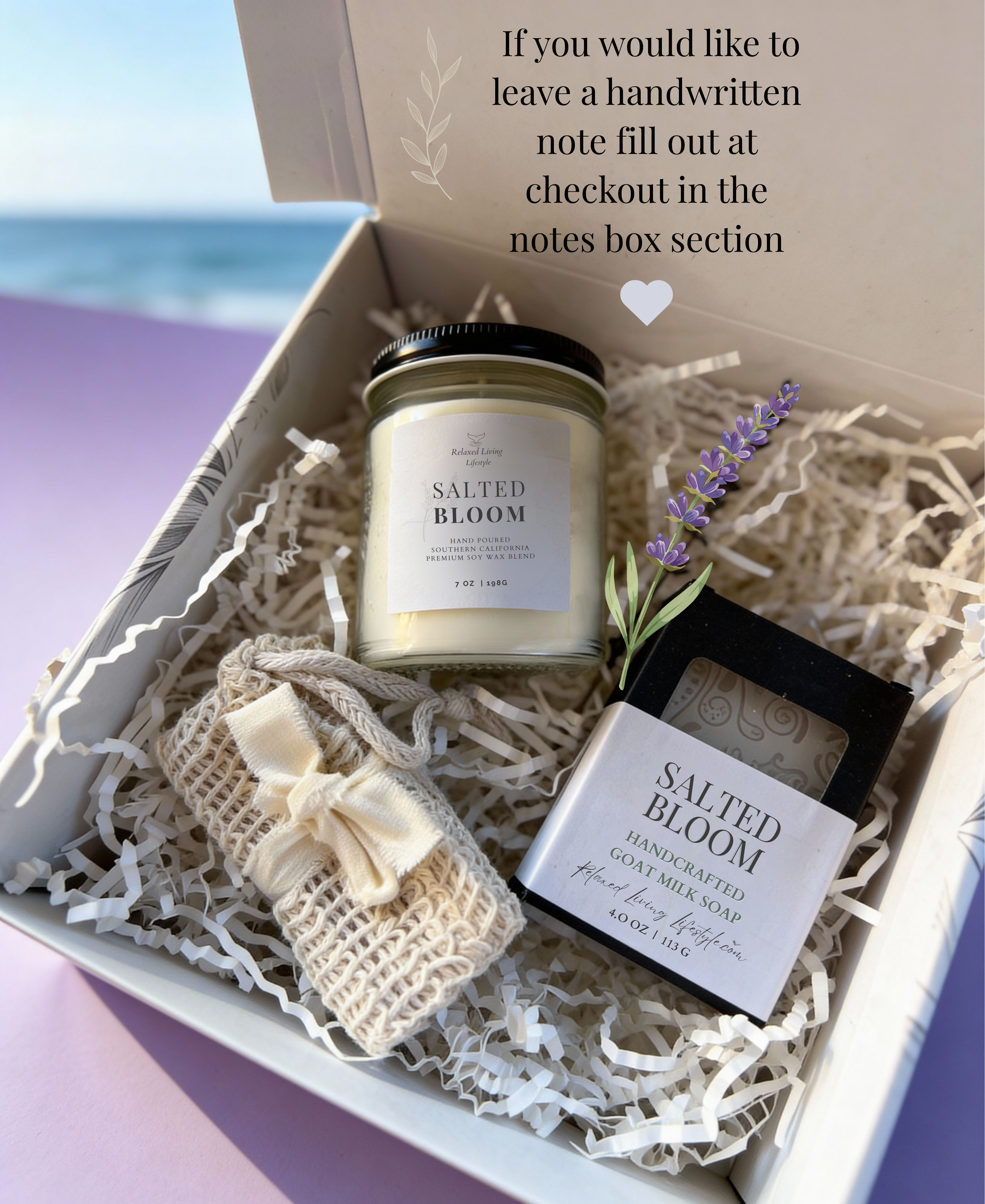 Close-up flat lay of Salted Bloom Gift Set featuring a coastal soy candle, goat milk soap, and natural soap saver bag inside a branded gift box, with a soft ocean view to the left. Artisan self-care gift with calming citrus and lavender scent notes.