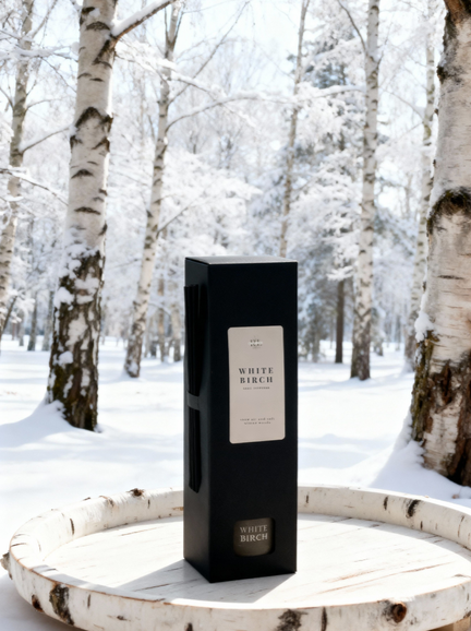 “White Birch reed diffuser gift-ready in its box with a snowy birch tree forest background, showcasing a crisp, nature-inspired home fragrance.