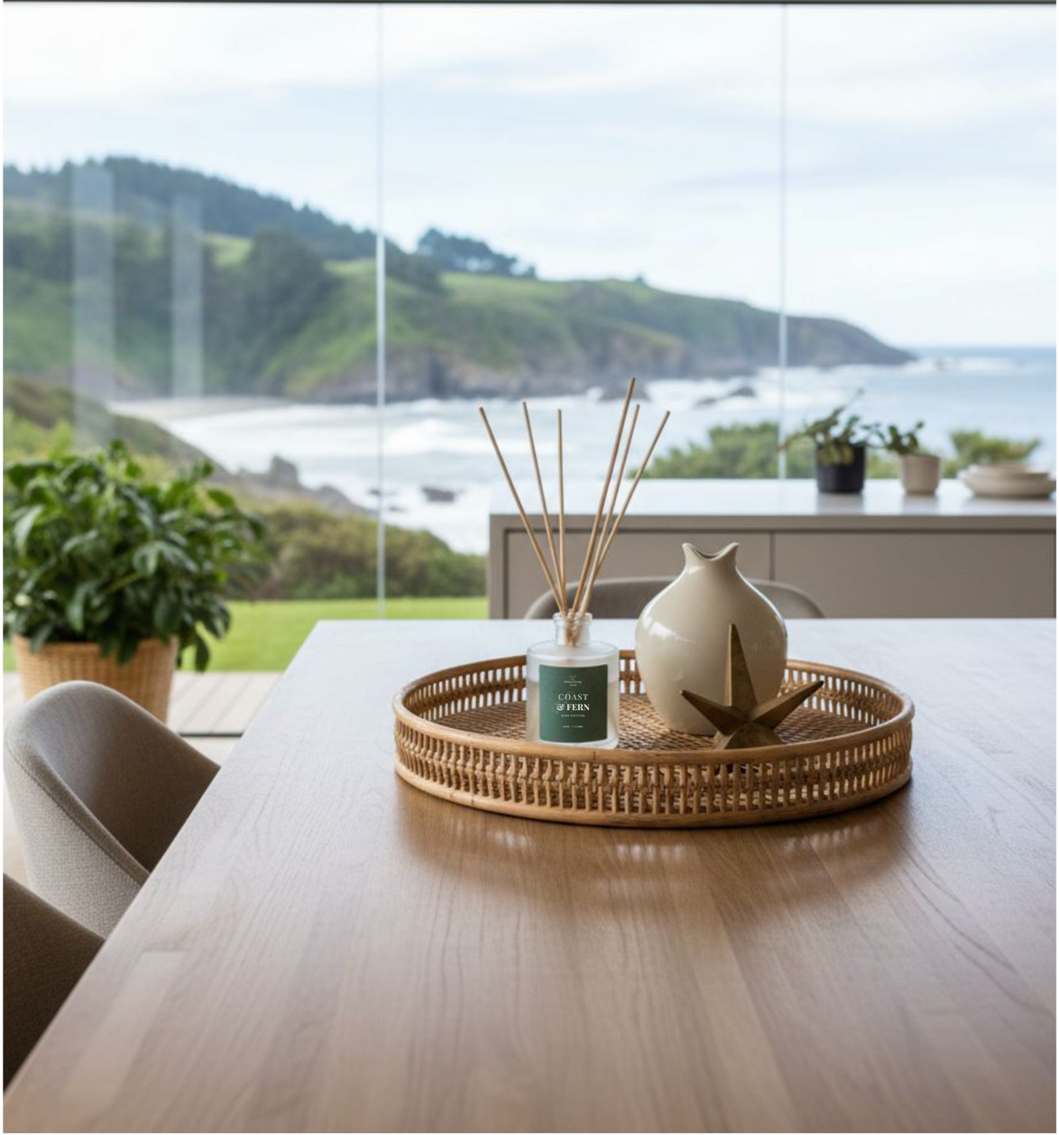 Coast & Fern Reed Diffuser in a rattan tray with decorative accents, styled with mountain and coastal view in background-natural, long-lasting home fragrance