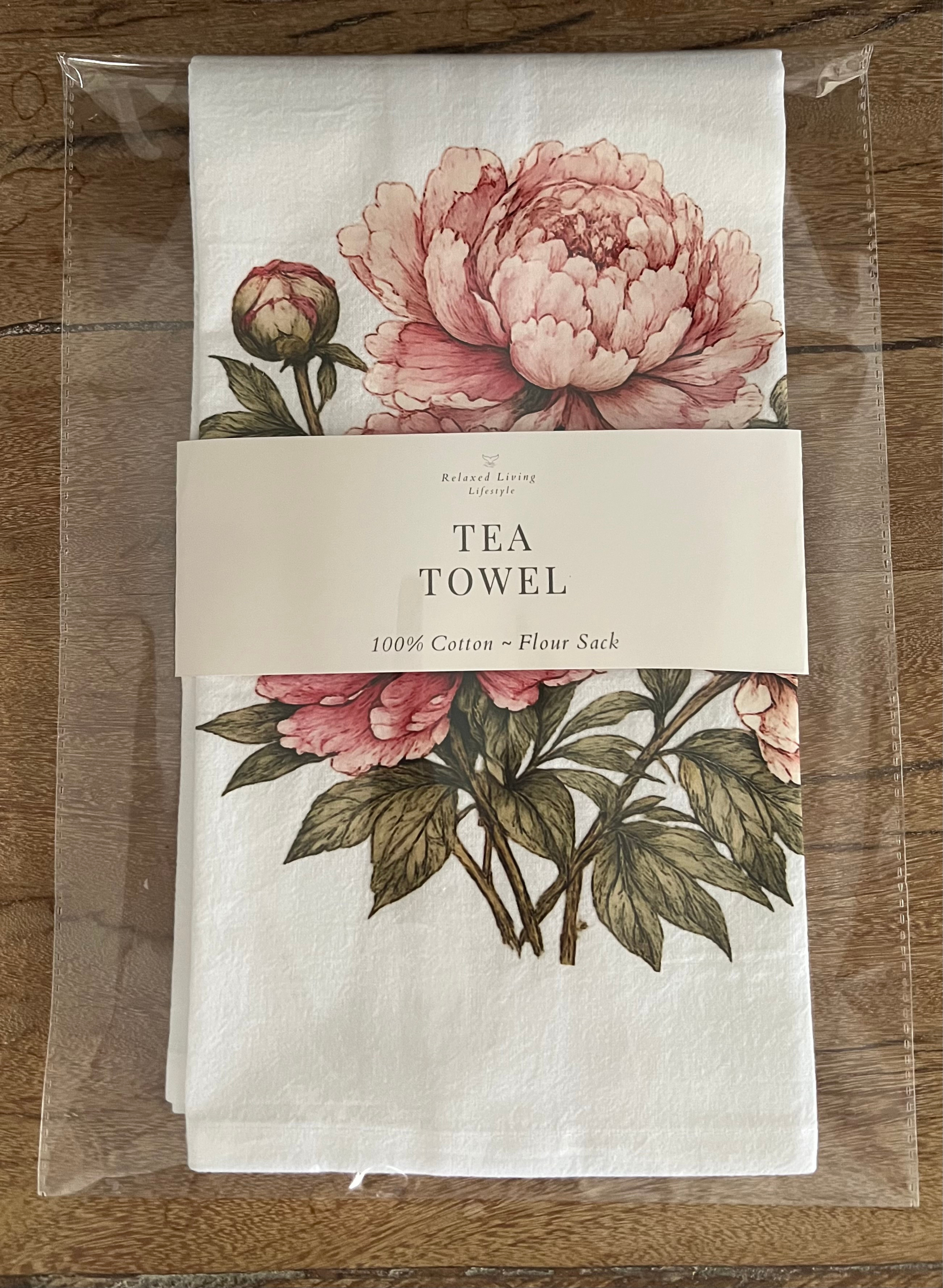 Close-up of packaged Peony cotton tea towel wrapped with branded band featuring elegant floral artwork on soft flour sack cotton kitchen towel for nature-inspired home décor and gifting