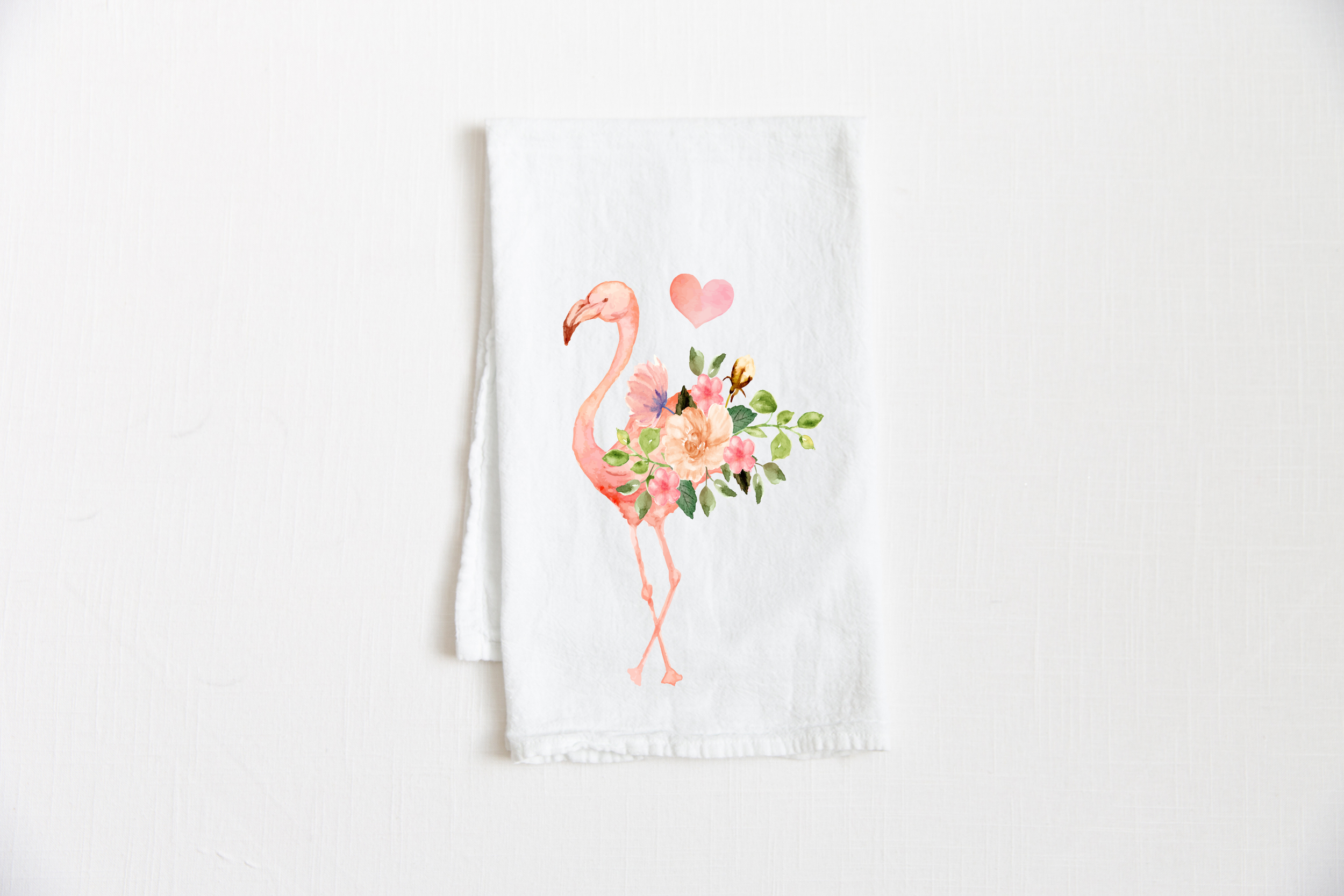 Flat lay of Flamingo & Florals Valentine’s Day tea towel featuring a watercolor flamingo with delicate florals and heart accent on a white background