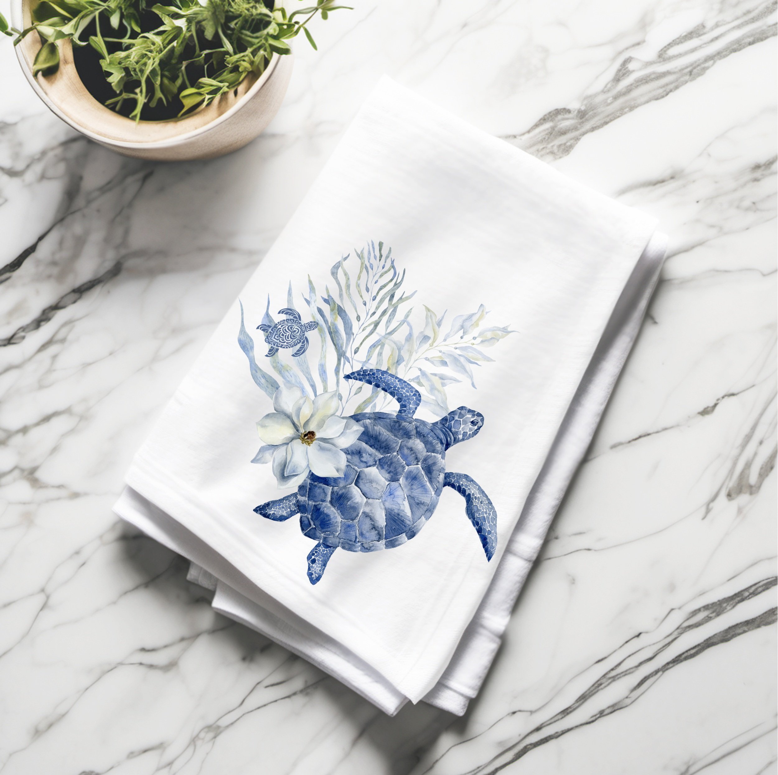 Folded cotton tea towel with watercolor sea turtle design, styled for coastal kitchen decor