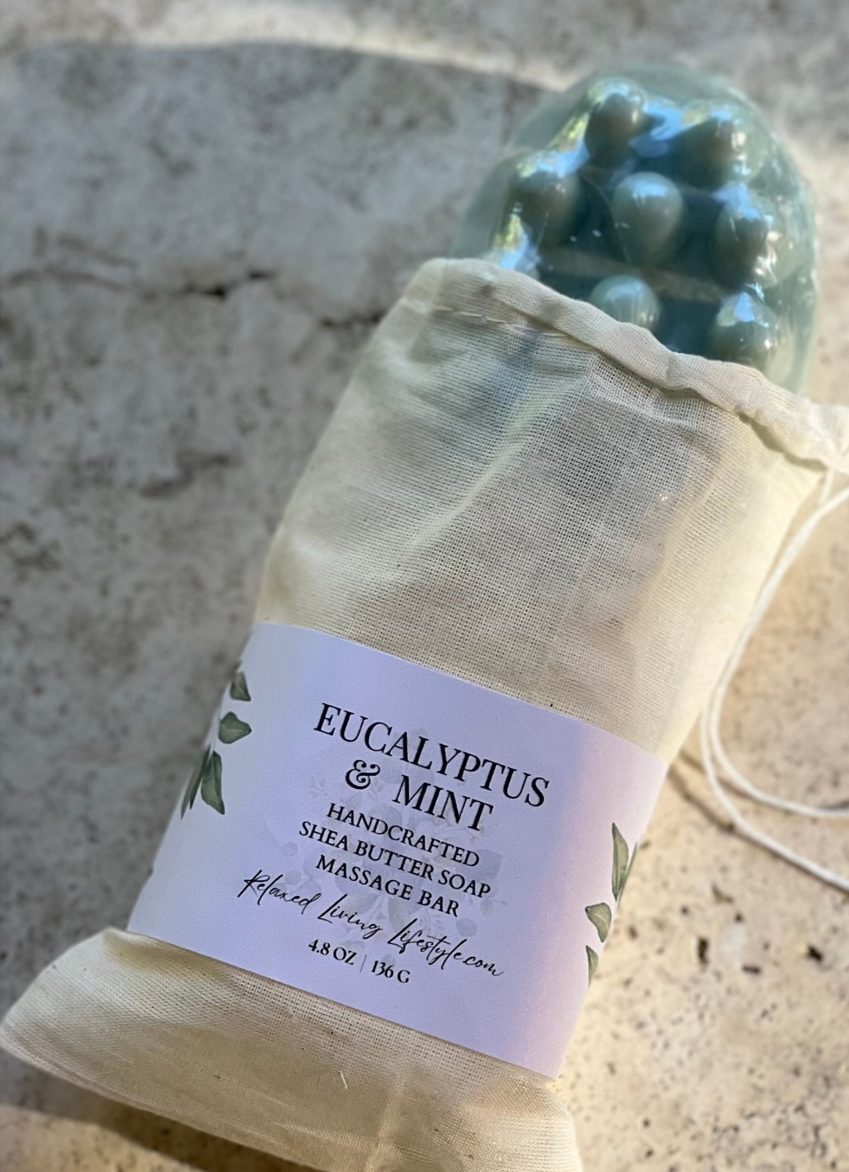 Eucalyptus & Mint shea butter massage bar with textured nubs partially extended from reusable cotton bag-handcrafted spa soap by Relaxed Living Lifestyle