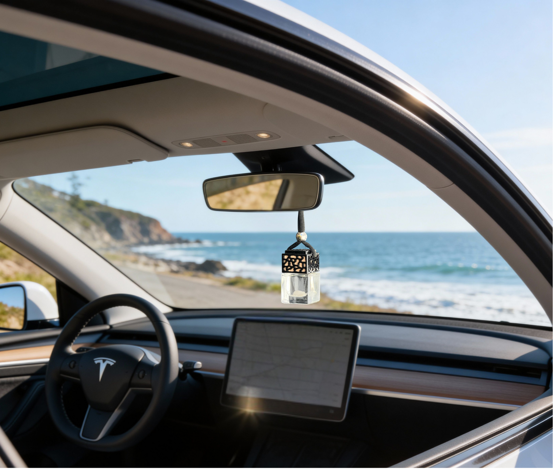 Hanging car fragrance diffuser on rearview mirror with ocean coastline view in the background