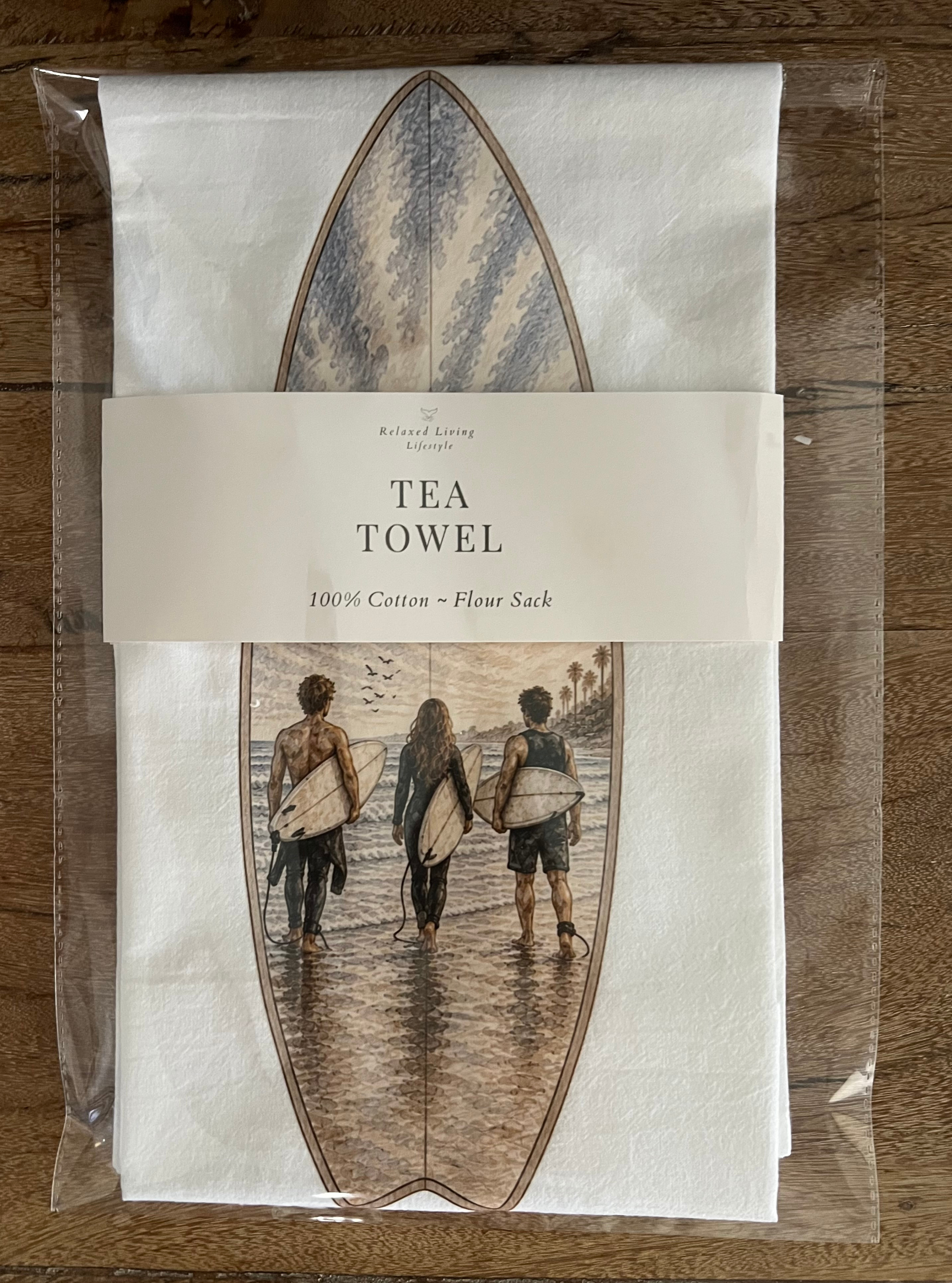 Hand-drawn Surfboard Surf tea towel featuring three surfers walking toward the ocean with surfboards, coastal kitchen decor and surfer gift packaged with tea towel band